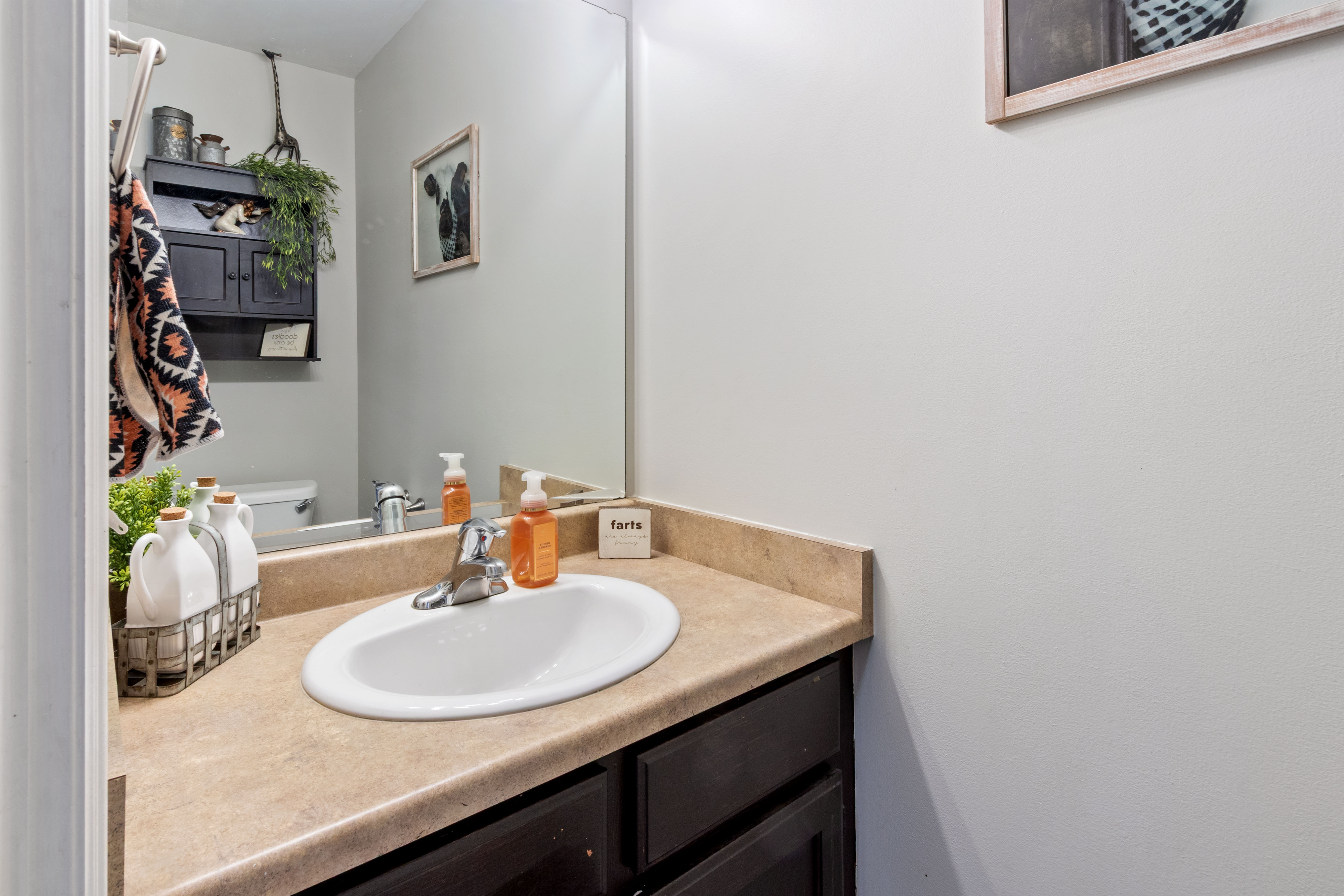 Vanity with integrated sink, laminate countertop, and dark wood-finish cabinetry