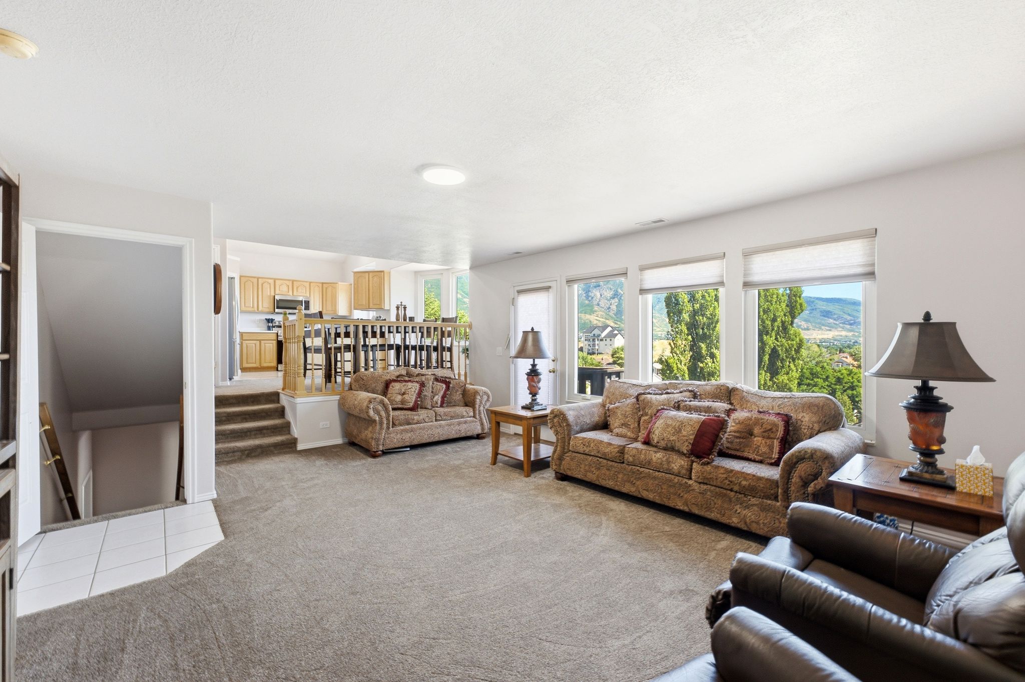 Spacious living area featuring neutral carpeting and abundant natural light from multiple windows