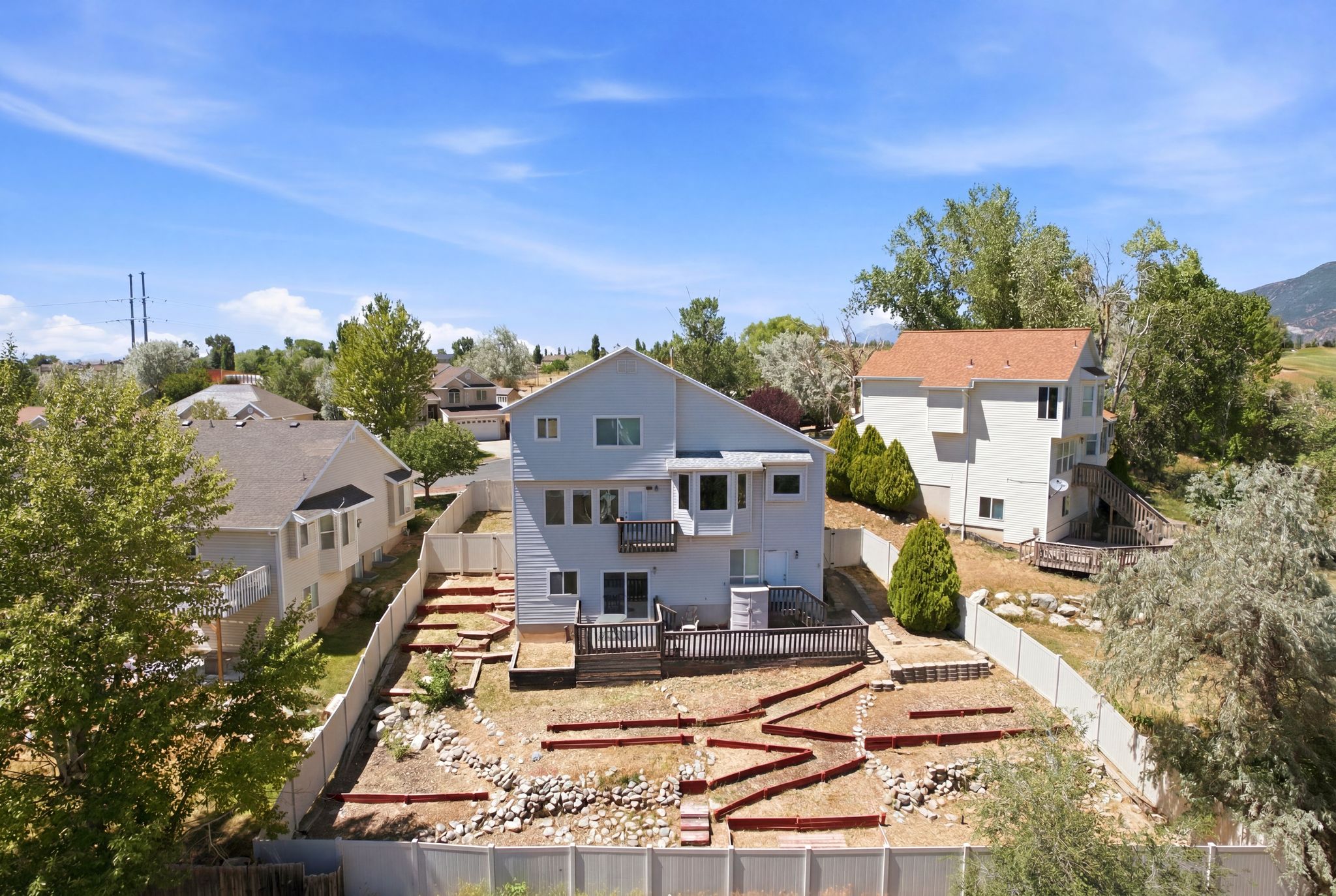 Rear exterior featuring a multi-level deck, lower patio area, and terraced landscaping