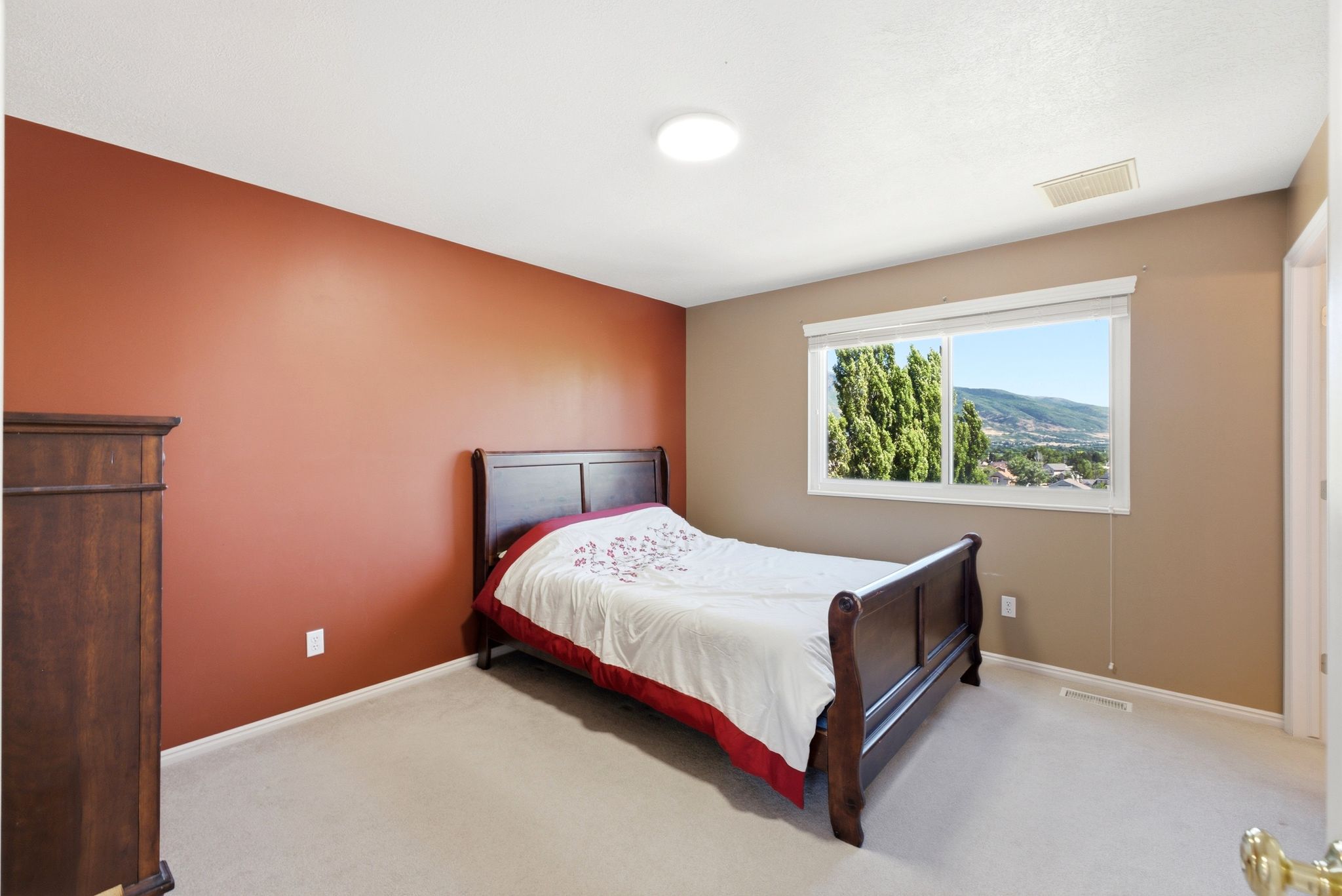 Carpeted bedroom with a single window featuring a distant mountain and city scenery