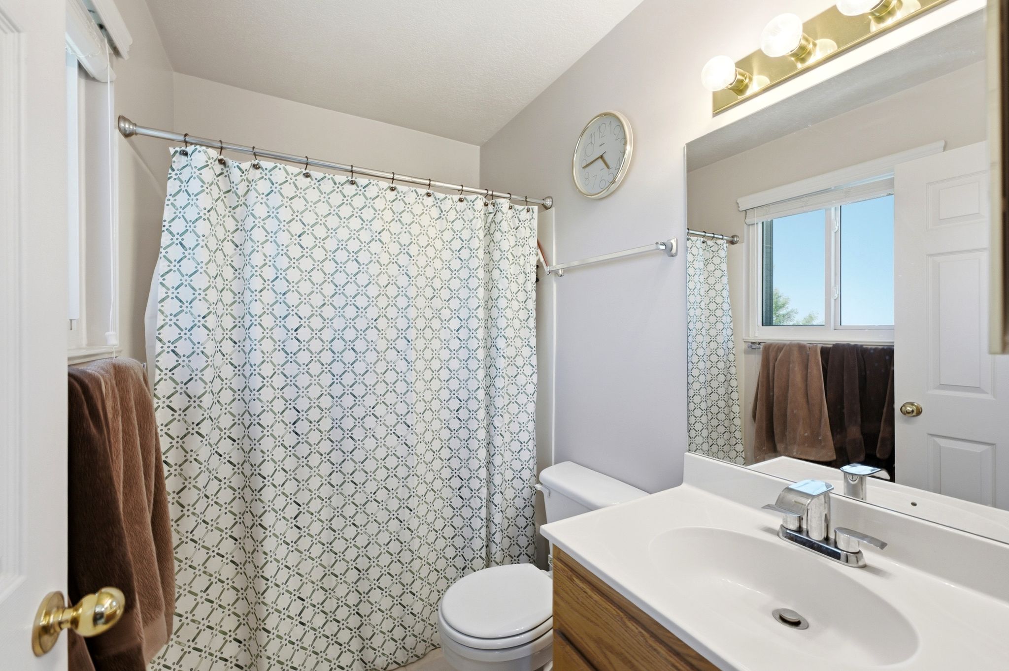 Bathroom featuring a wood-finish vanity with an integrated sink, polished chrome faucet, and overhead vanity lighting