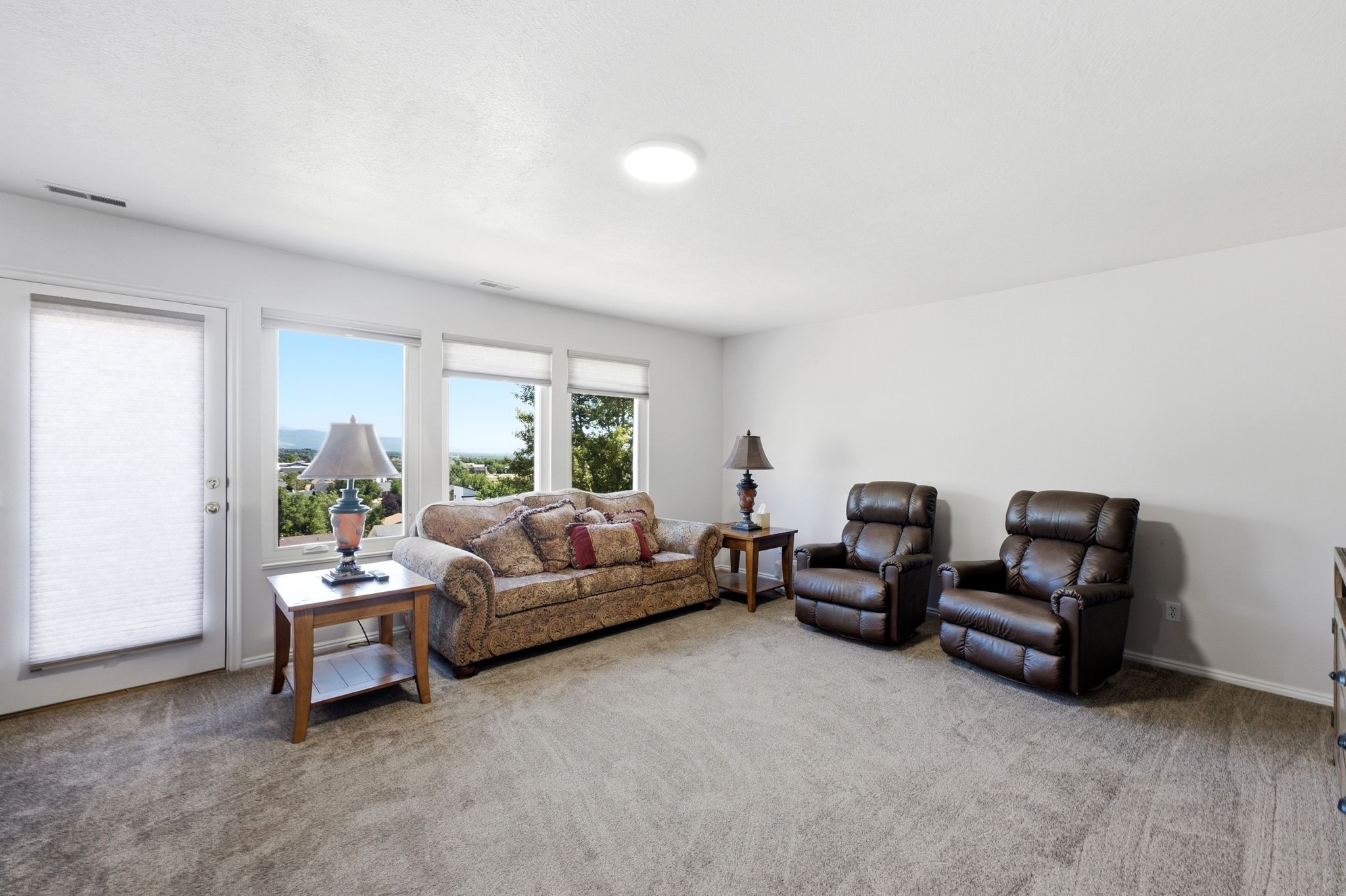 Spacious living area featuring light gray walls and neutral tone carpeting