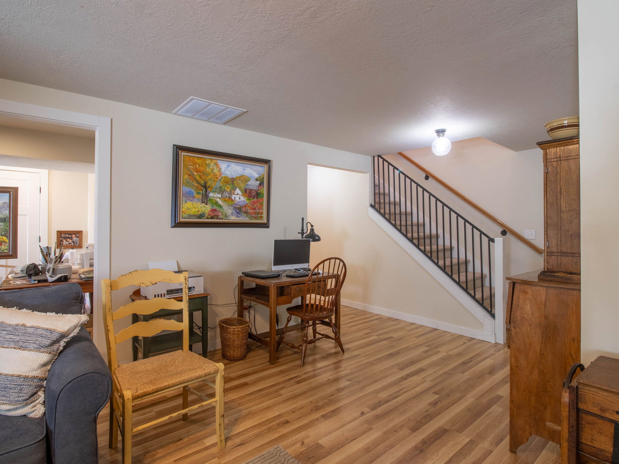 Hardwood-style flooring throughout, featuring a staircase with black metal balusters and a wood handrail