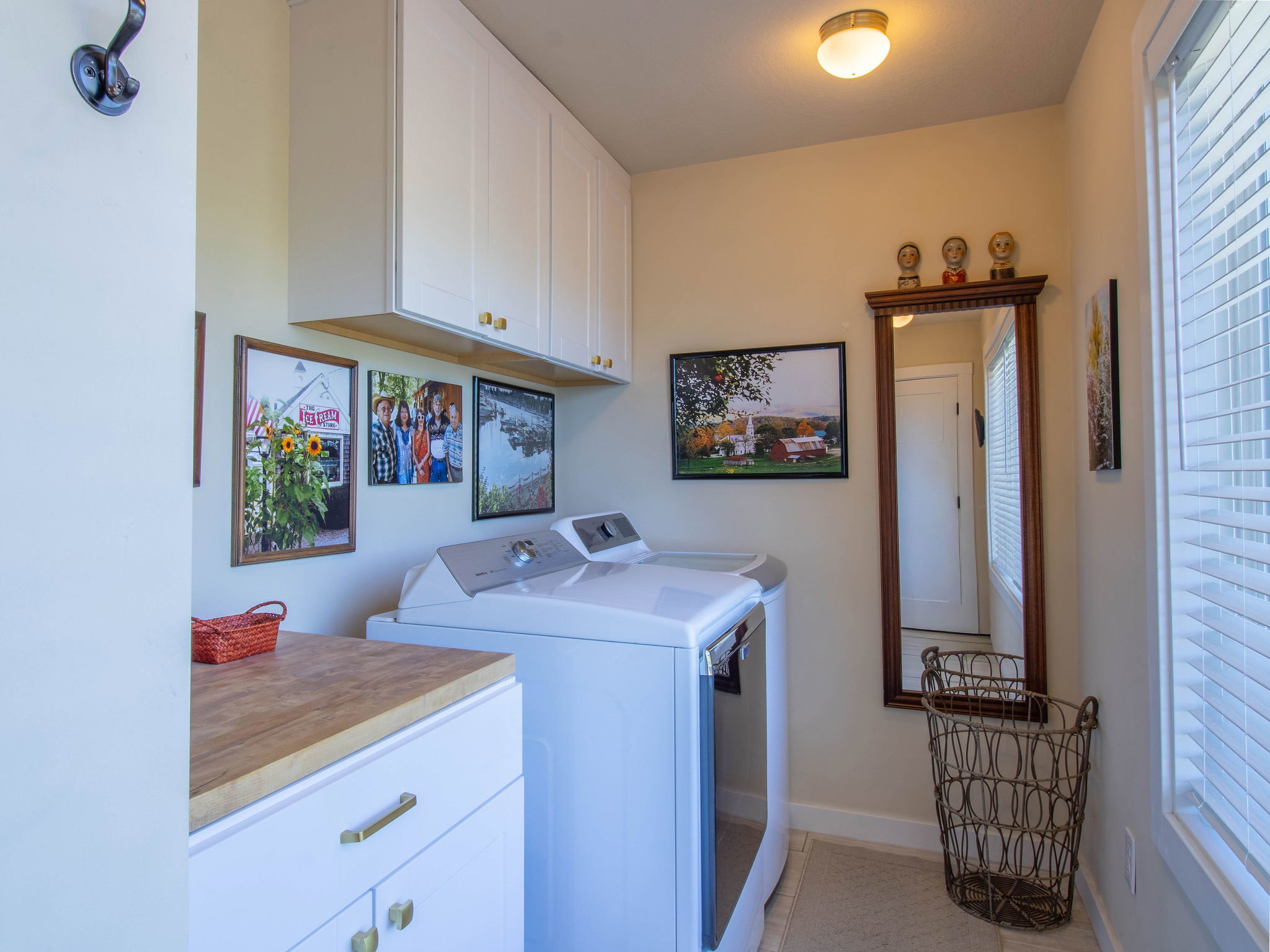 Utility room featuring white cabinetry with gold-tone hardware, a wood-finish countertop, and neutral wall paint