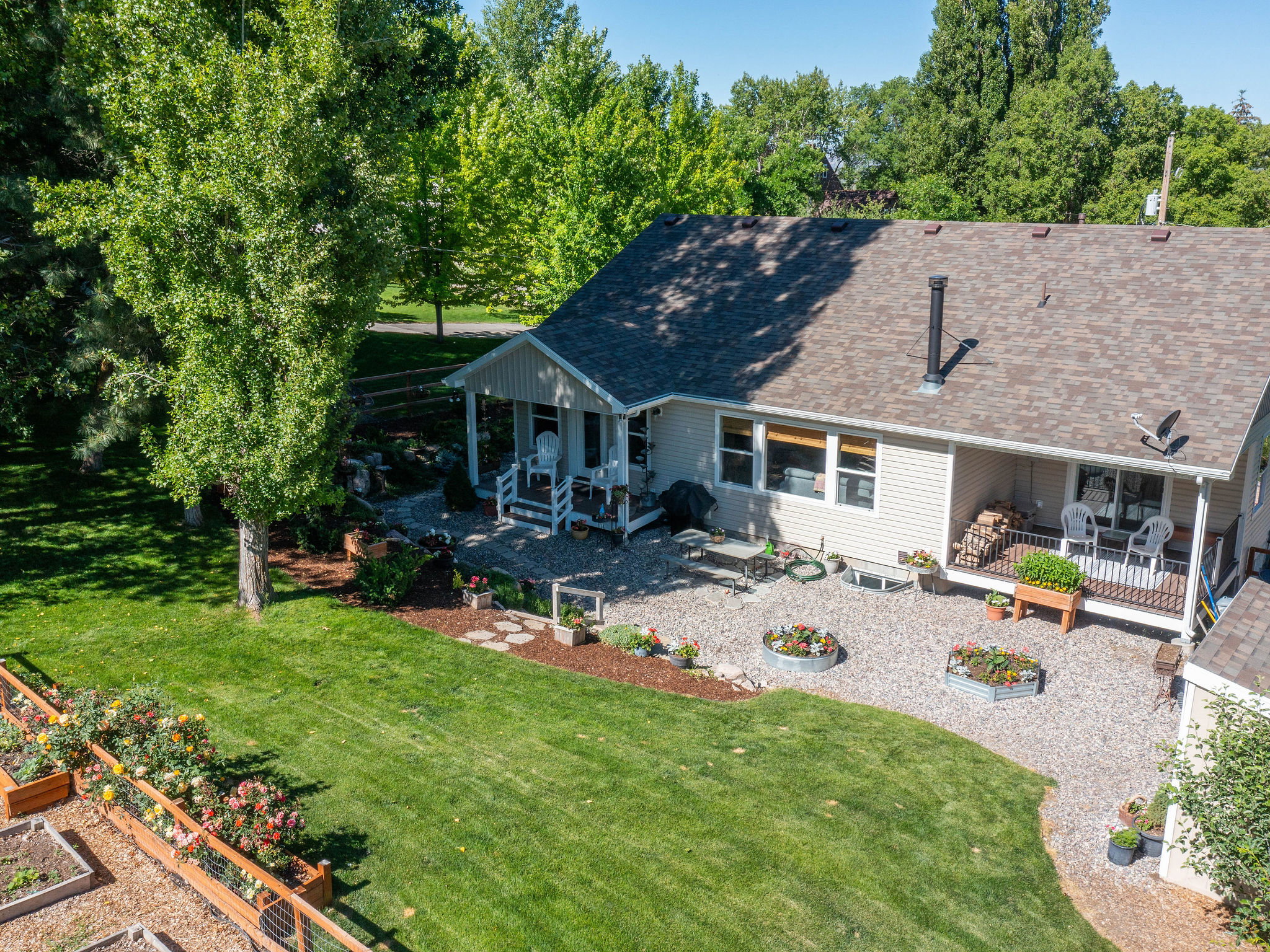 Expansive backyard featuring a manicured lawn, gravel patio area, and raised garden beds