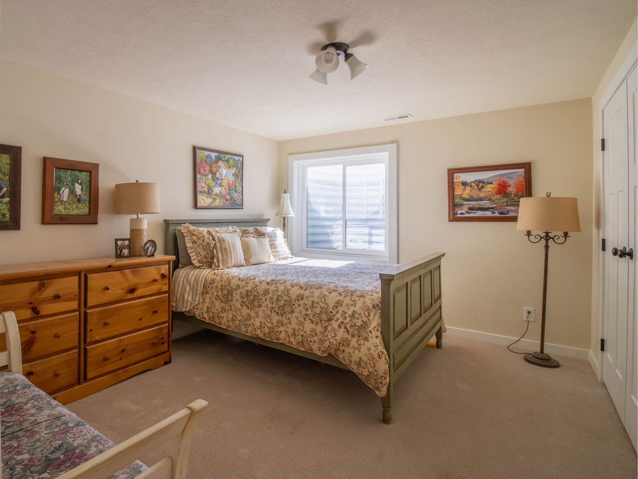Carpeted room featuring a white-framed window with horizontal blinds, light-colored walls, and a ceiling fan with three directional lights