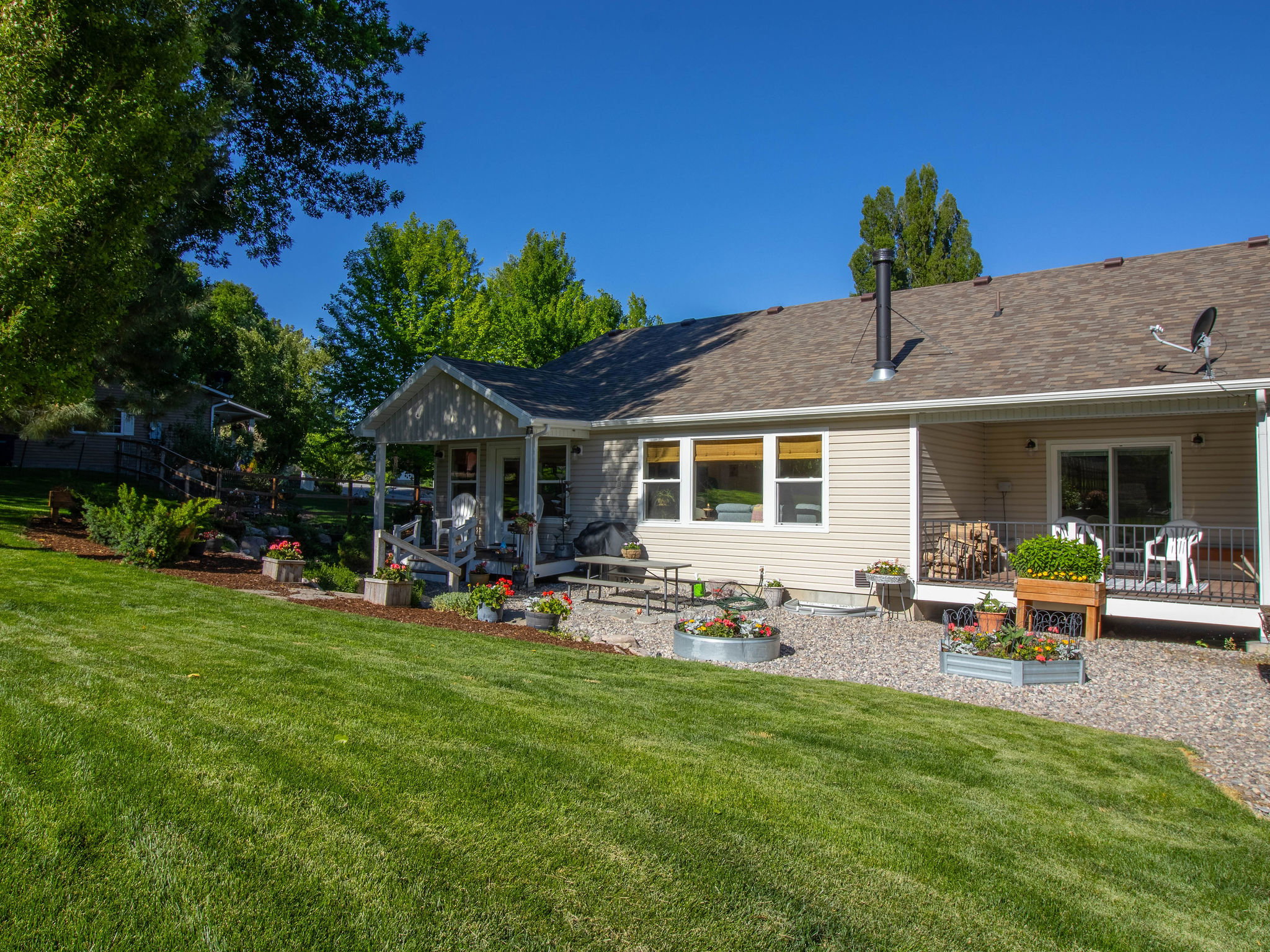 Expansive backyard featuring a lush lawn, a covered patio, and a gravel hardscape area
