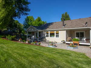 Expansive backyard featuring a lush lawn, a covered patio, and a gravel hardscape area