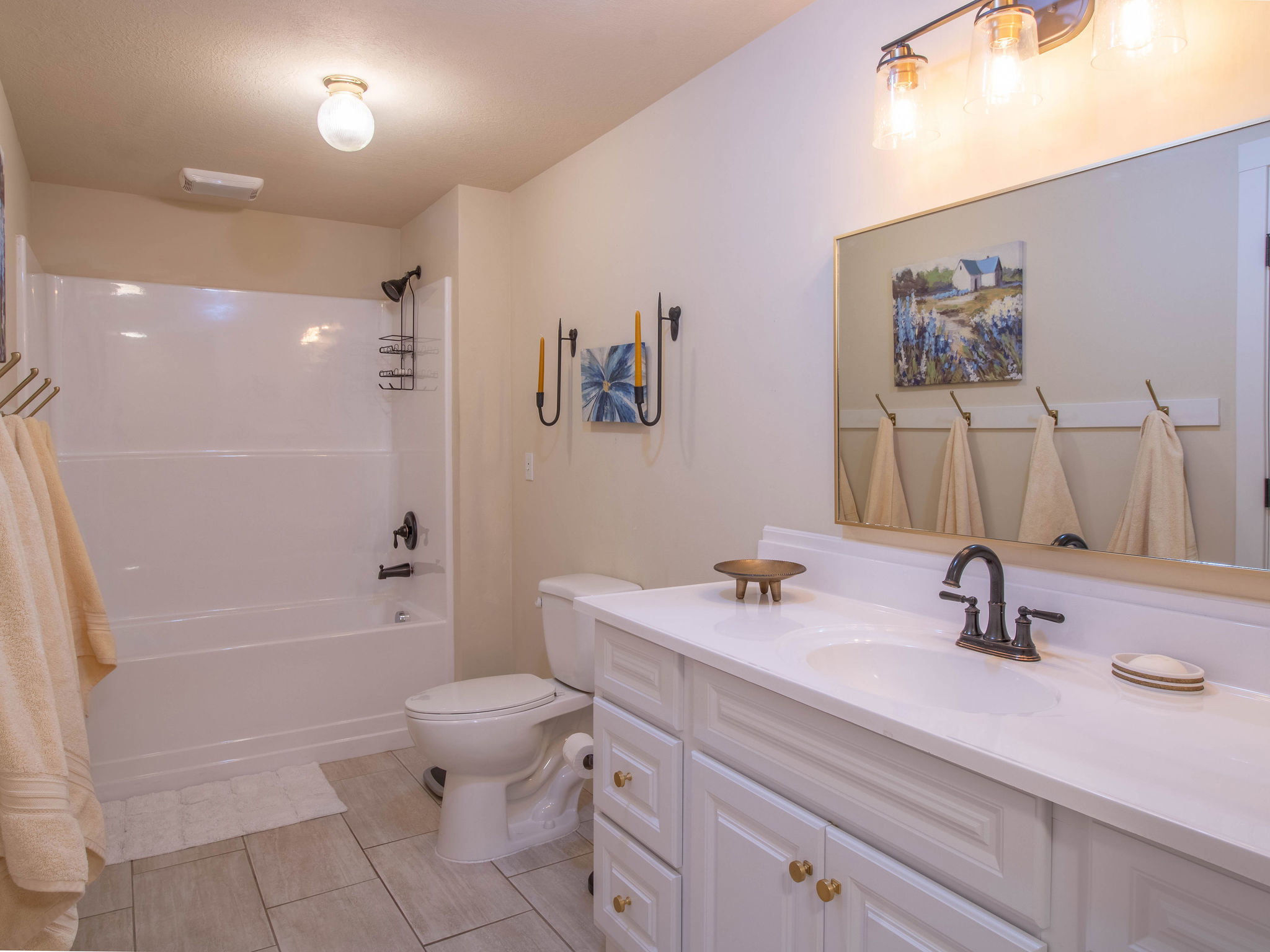 Bathroom featuring a white vanity with gold-toned hardware, an integrated sink, and a dark-toned faucet