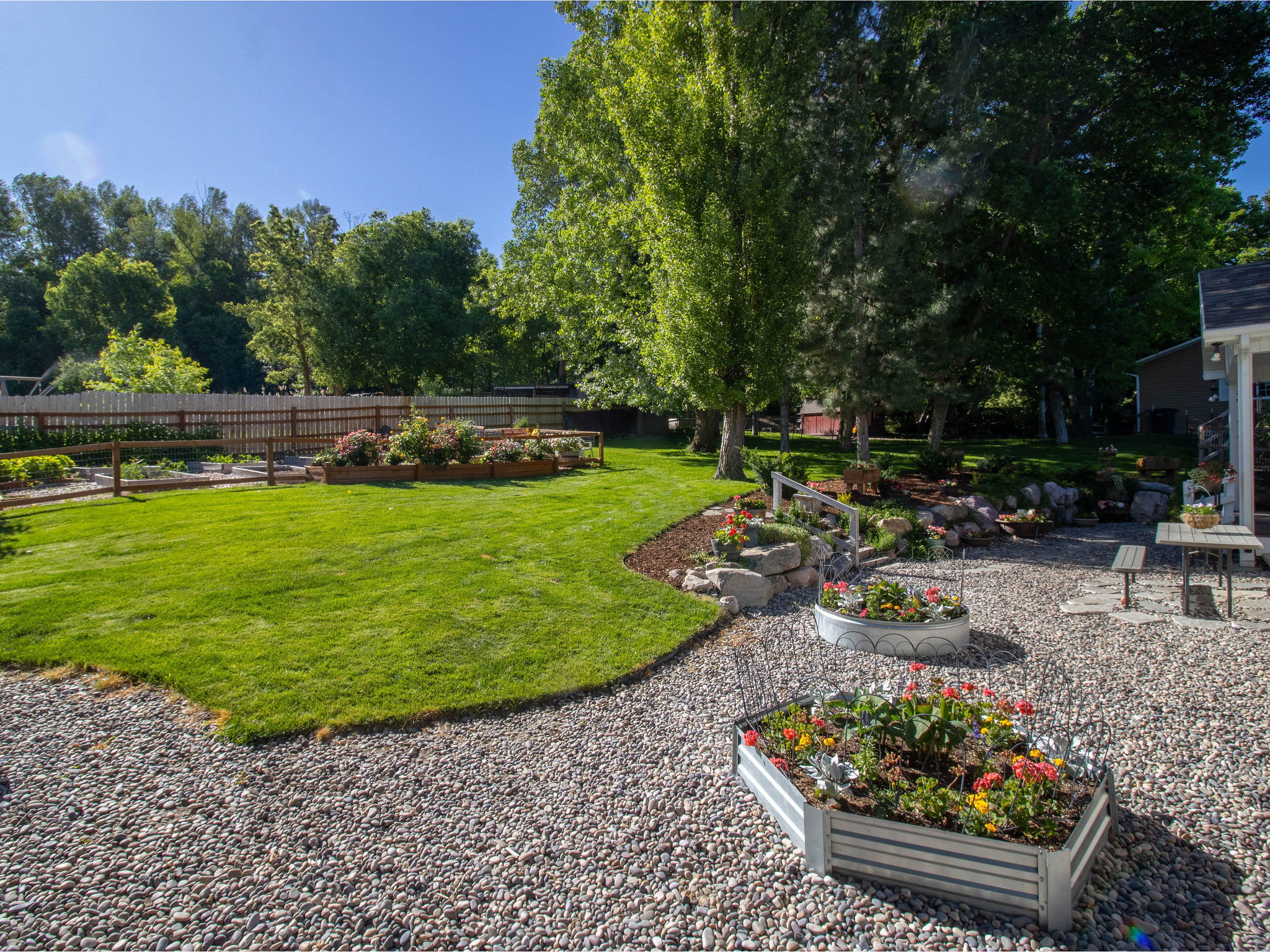 Expansive backyard featuring a manicured lawn, established trees, and decorative rock landscaping