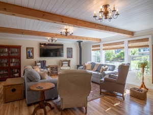 Spacious room featuring wood-finish flooring, exposed wood beams, and a shiplap ceiling