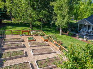 Expansive backyard featuring multiple raised garden beds, a gravel-covered cultivation area, and a wood-slat fence