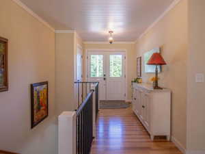 Entryway featuring wood-finish flooring, white double doors with upper glass panels, and a beadboard ceiling