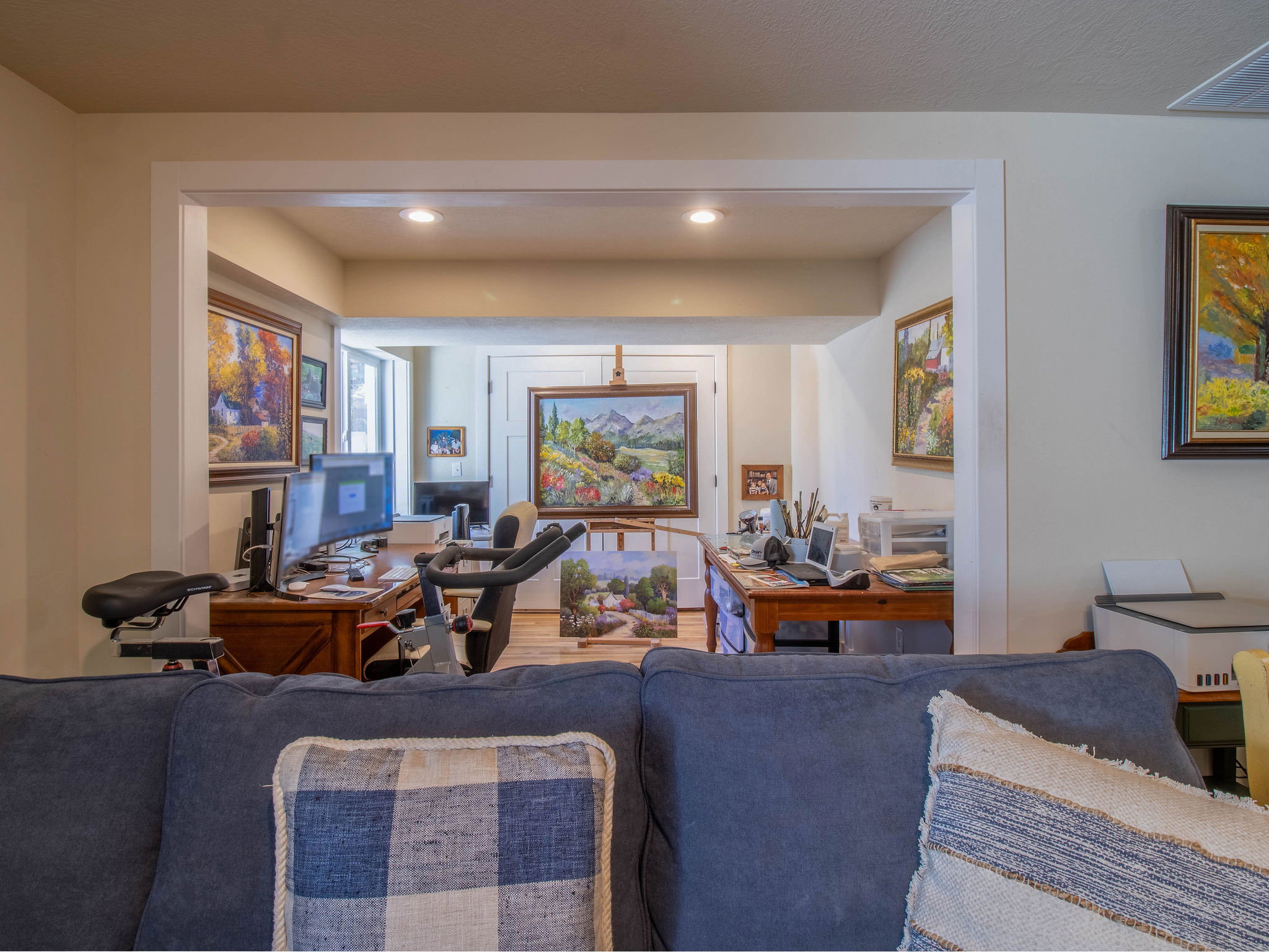 Recessed lighting illuminates this versatile interior space with warm beige walls and light wood-finish flooring