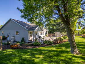 Expansive backyard featuring a manicured lawn, established shade trees, and a gravel patio area