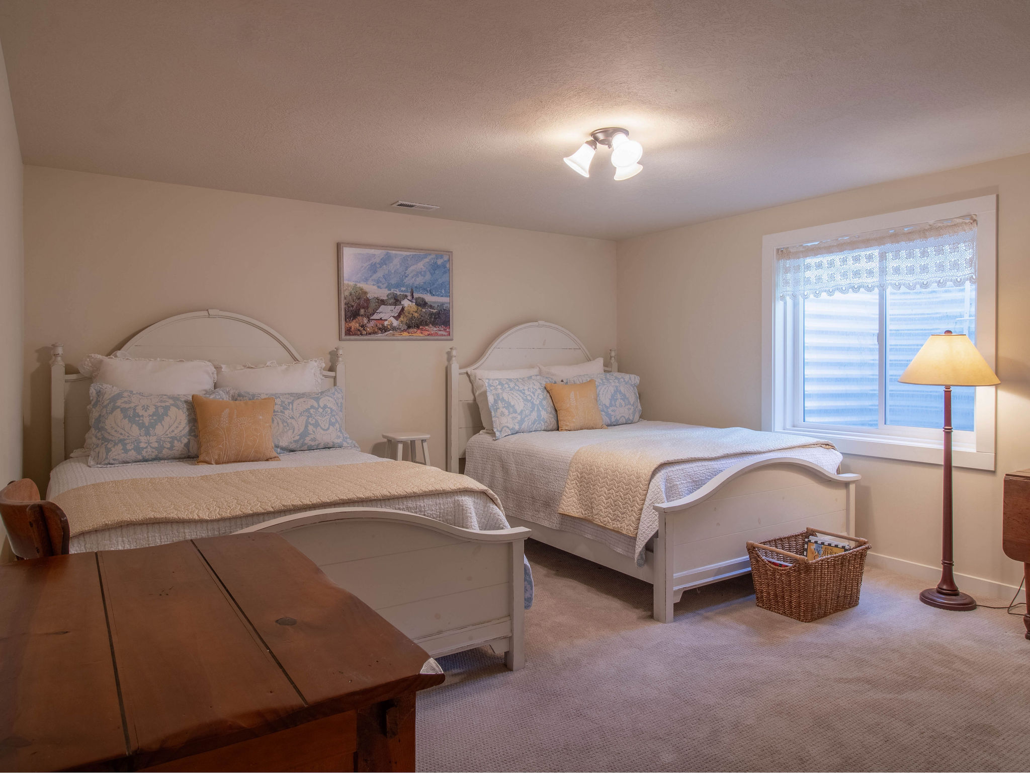 Carpeted room featuring two beds with white headboards and footboards, a window with horizontal blinds, and a semi-flush ceiling light fixture