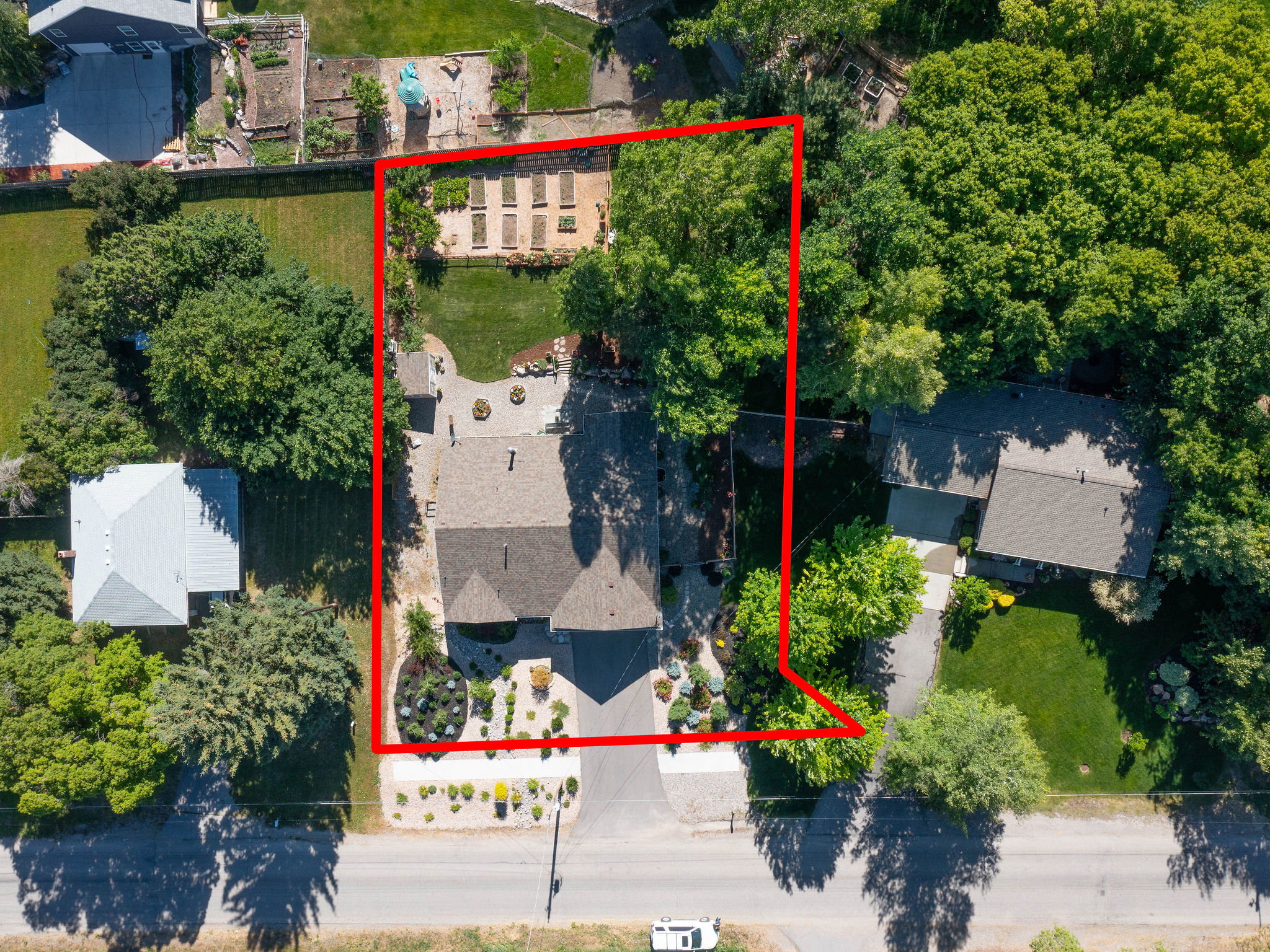 Aerial property overview showcasing a residential structure with a dark-pitched roof and a front-facing driveway