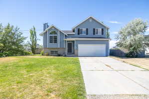 Two-story residence featuring light blue siding with white trim, a two-car garage, and a concrete driveway
