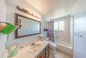 Bathroom featuring a vanity with an integrated sink, a large framed mirror, a four-bulb vanity light fixture, a shower-over-tub with white subway tile surround, and a window