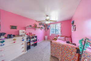 Carpeted room featuring a ceiling fan, window with curtains, and built-in wall shelving