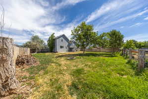 Expansive backyard featuring a partial wood privacy fence and mature trees