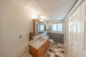 Bathroom featuring a wood-finish vanity with an integrated sink and light-toned countertop, a wall-mounted medicine cabinet, and a window