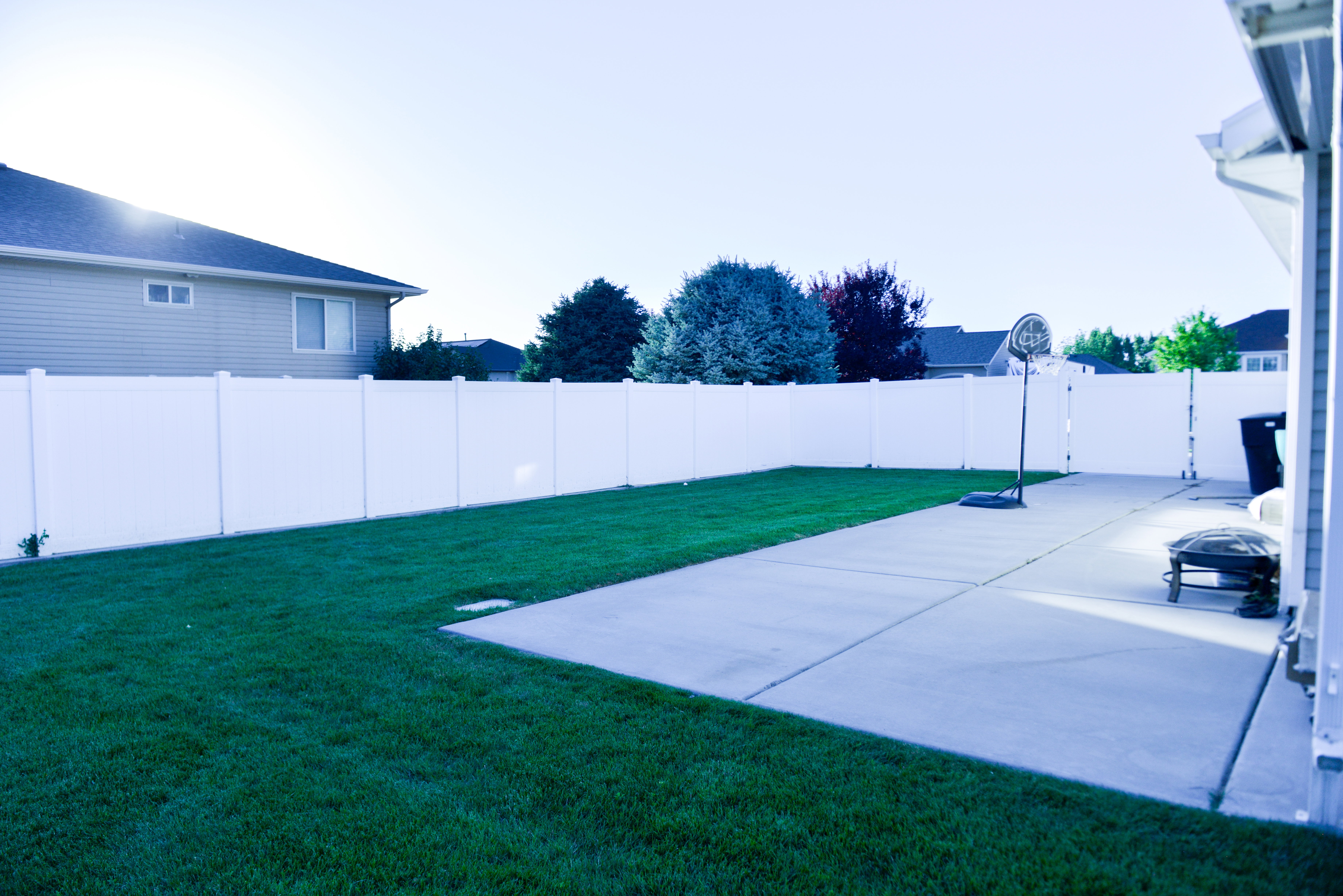 Expansive backyard featuring a large concrete patio and a manicured lawn