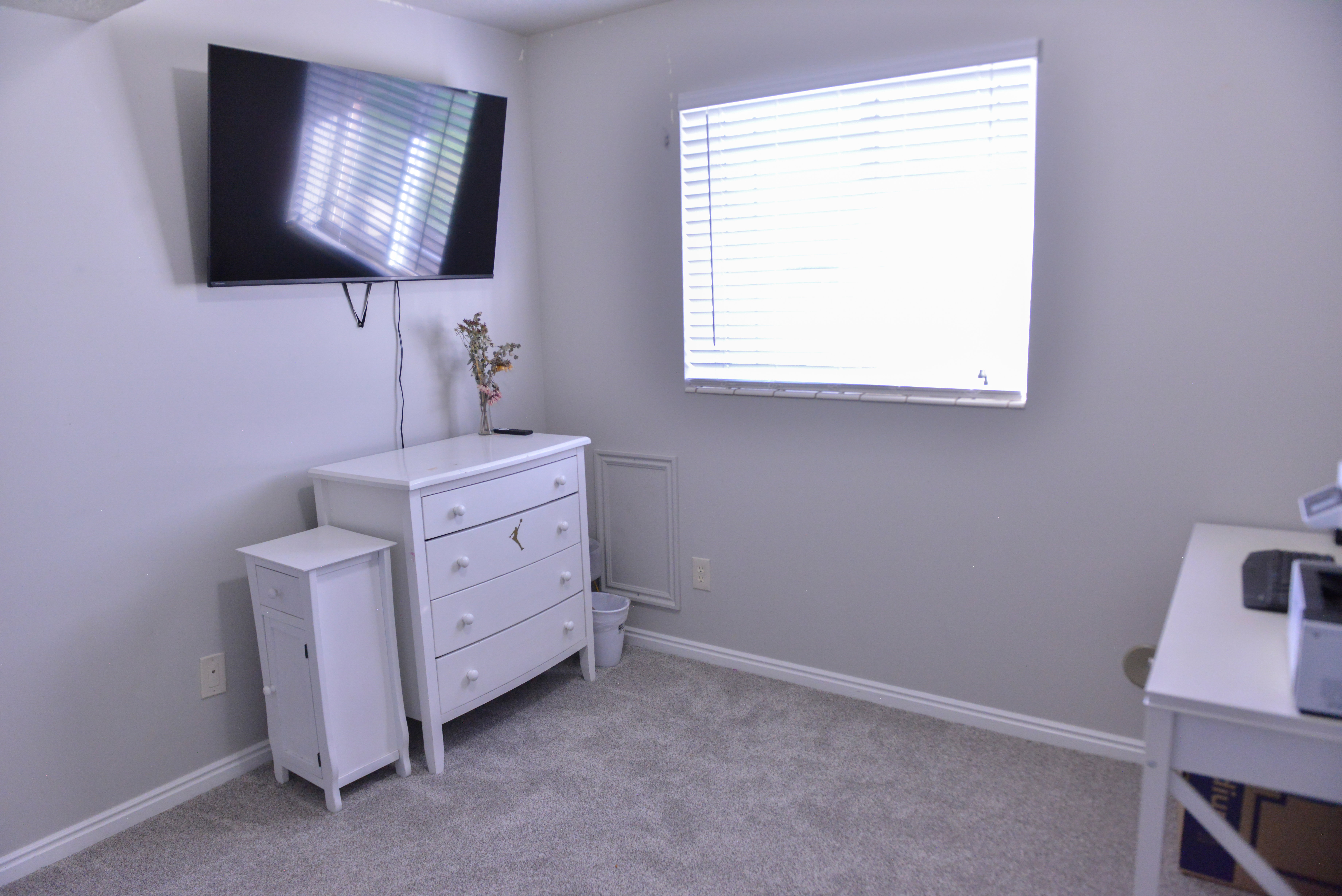 Carpeted room featuring a single window with horizontal blinds, light grey walls, and white baseboards