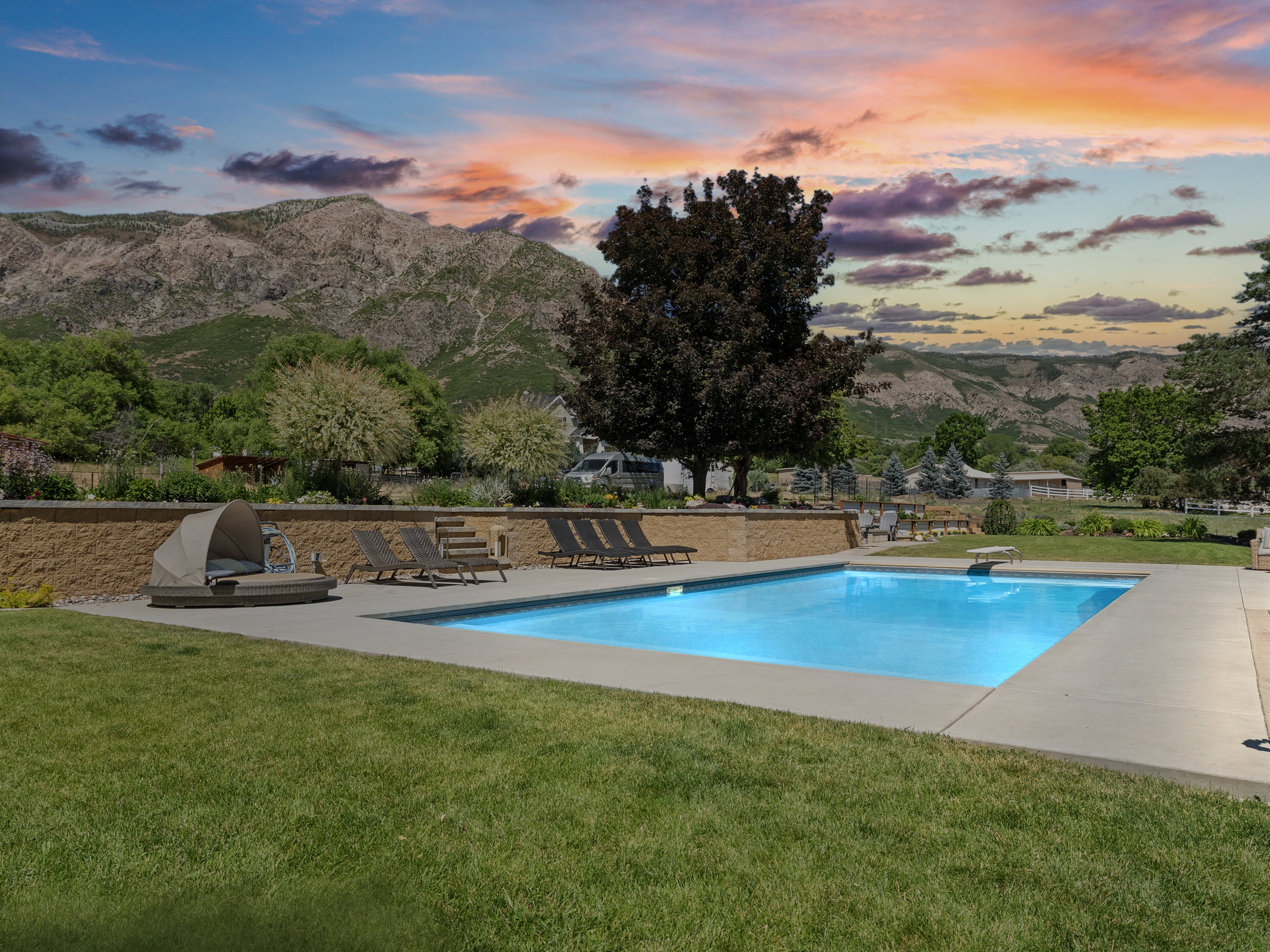 Rectangular inground swimming pool with a diving board, surrounded by a concrete patio and manicured lawn