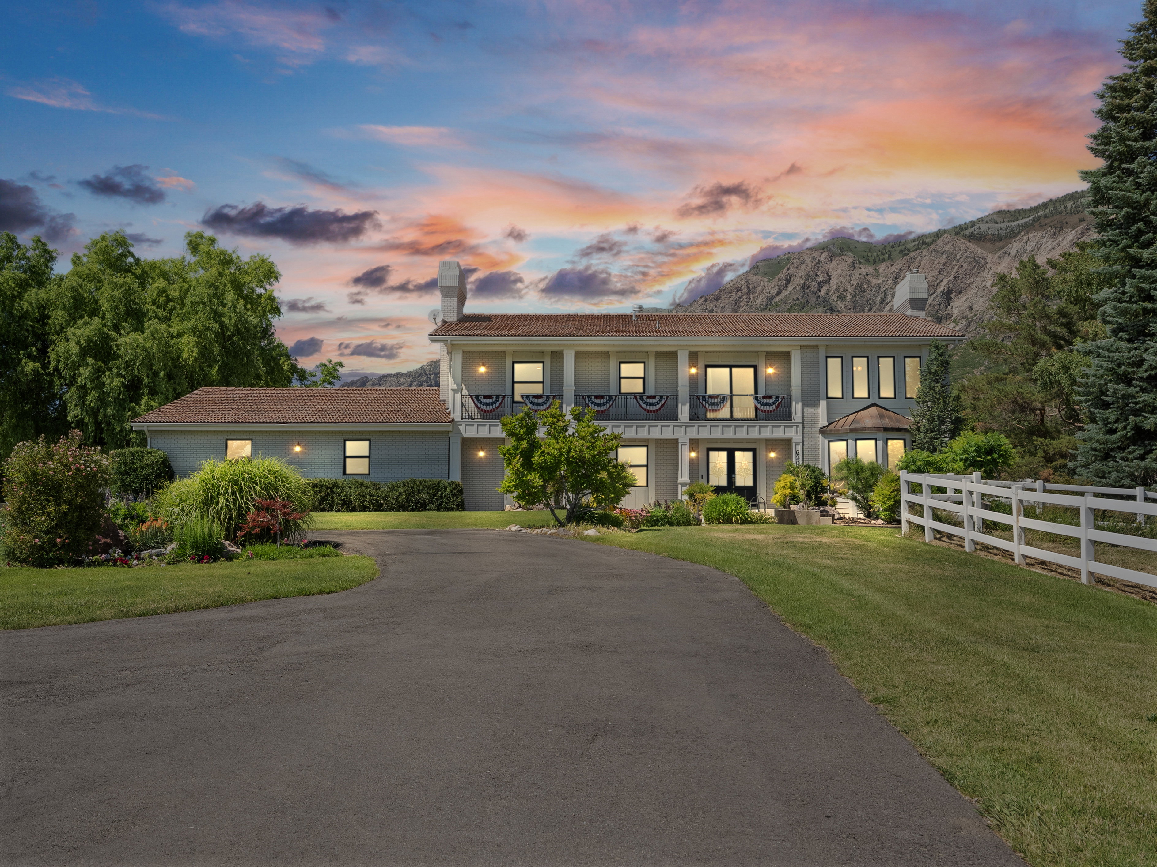 Two-story residence featuring a paved driveway, multiple windows, and a second-story balcony