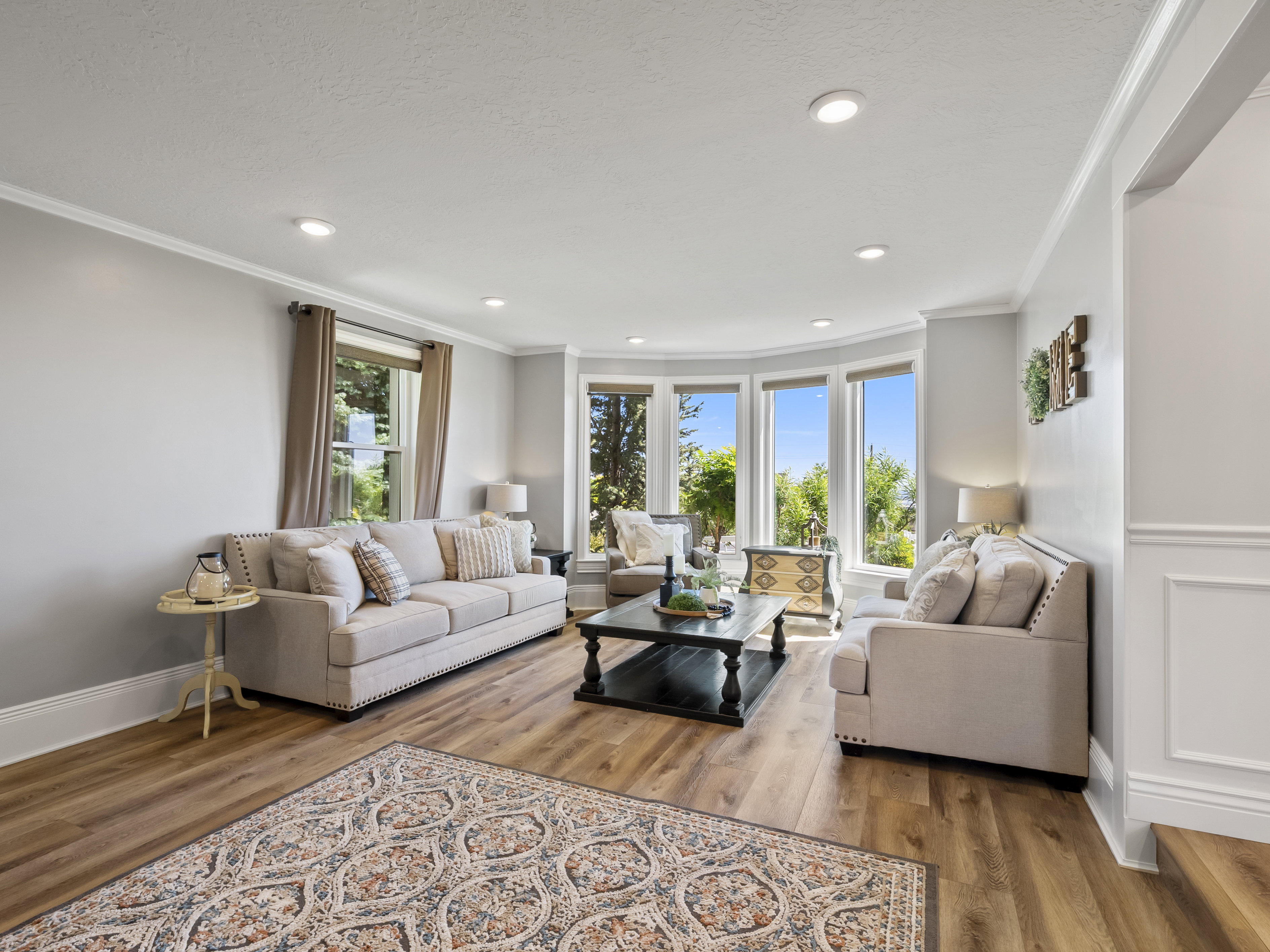 Living area featuring wood-finish flooring, recessed lighting, crown molding, and a bay window