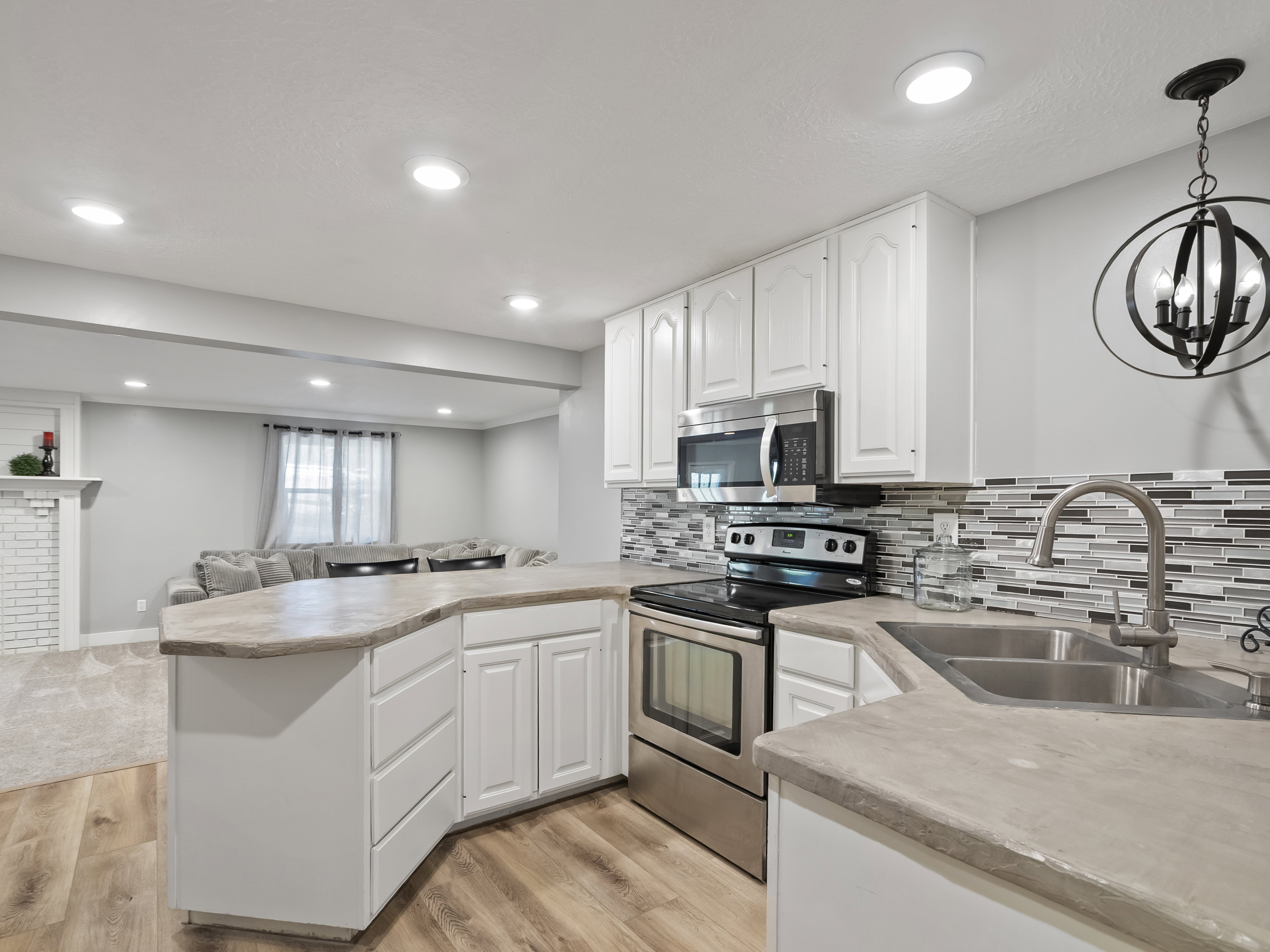 Modern kitchen featuring white cabinetry, stainless steel appliances, a mosaic tile backsplash, and a double basin sink with a gooseneck faucet