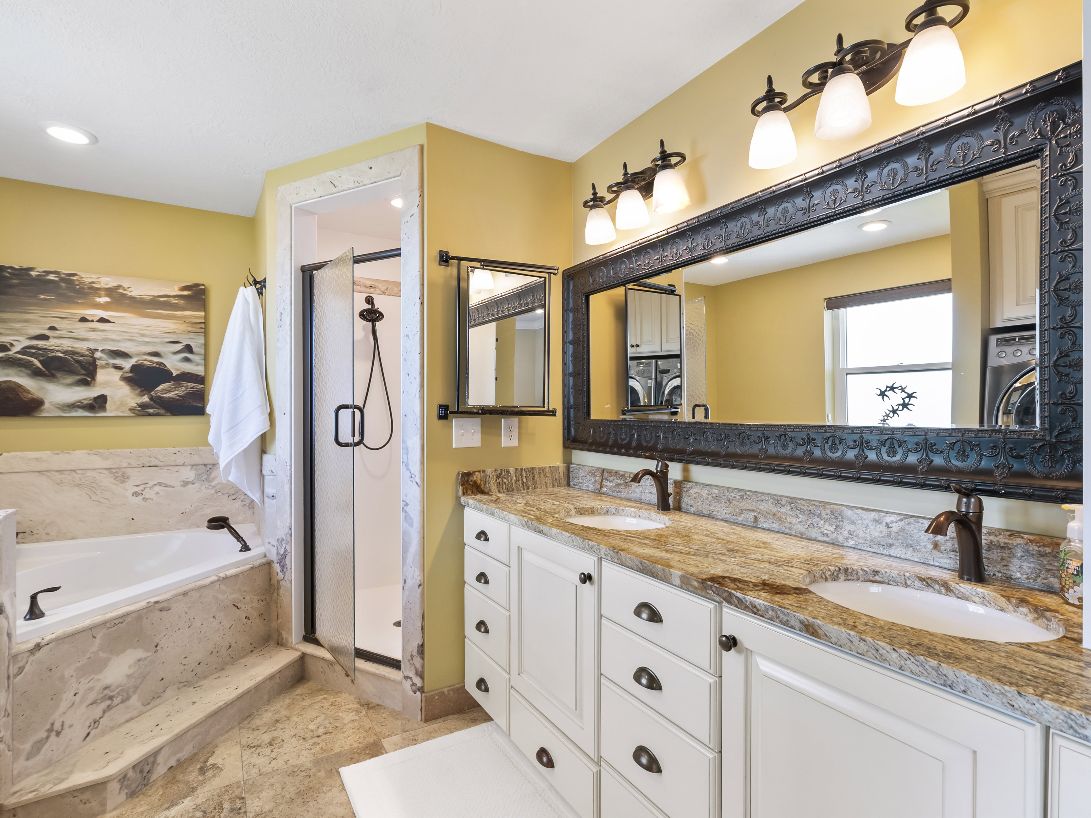 Dual vanity featuring white cabinetry, granite countertops, and bronze fixtures
