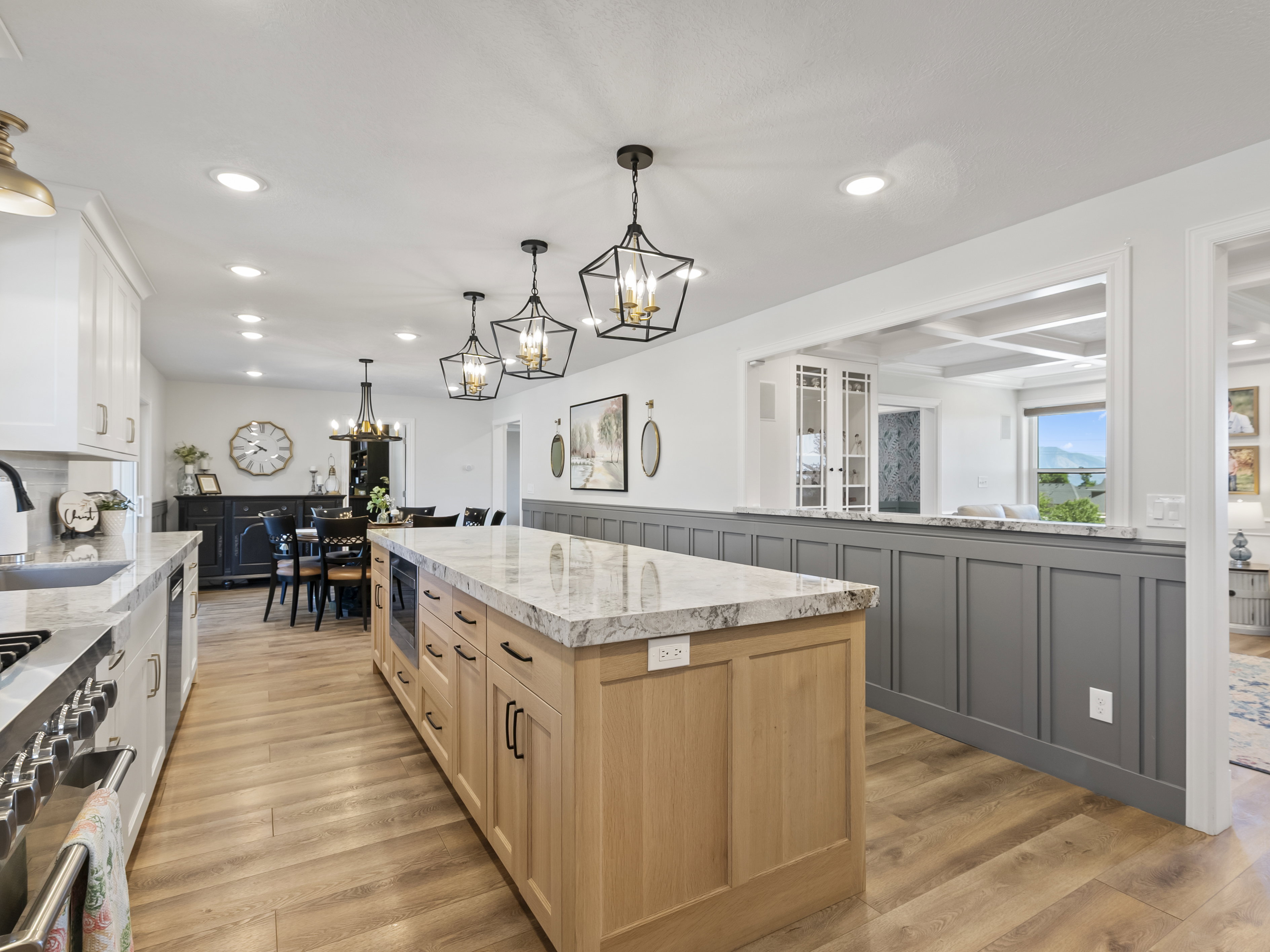 Spacious kitchen featuring a large light wood-finish island with integrated microwave, granite countertops, and recessed lighting