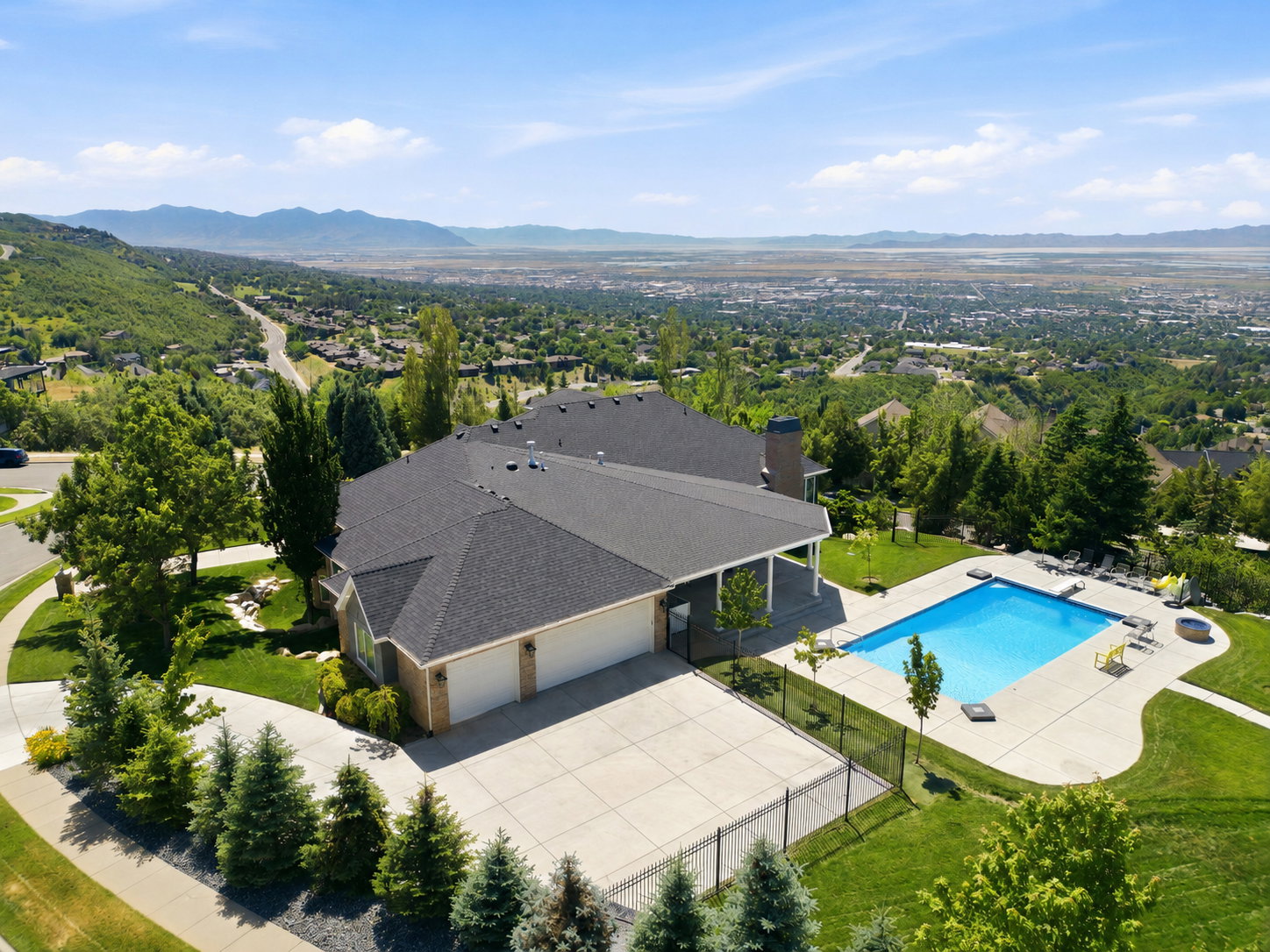 Expansive backyard with a rectangular swimming pool, concrete patio, and lush green lawn