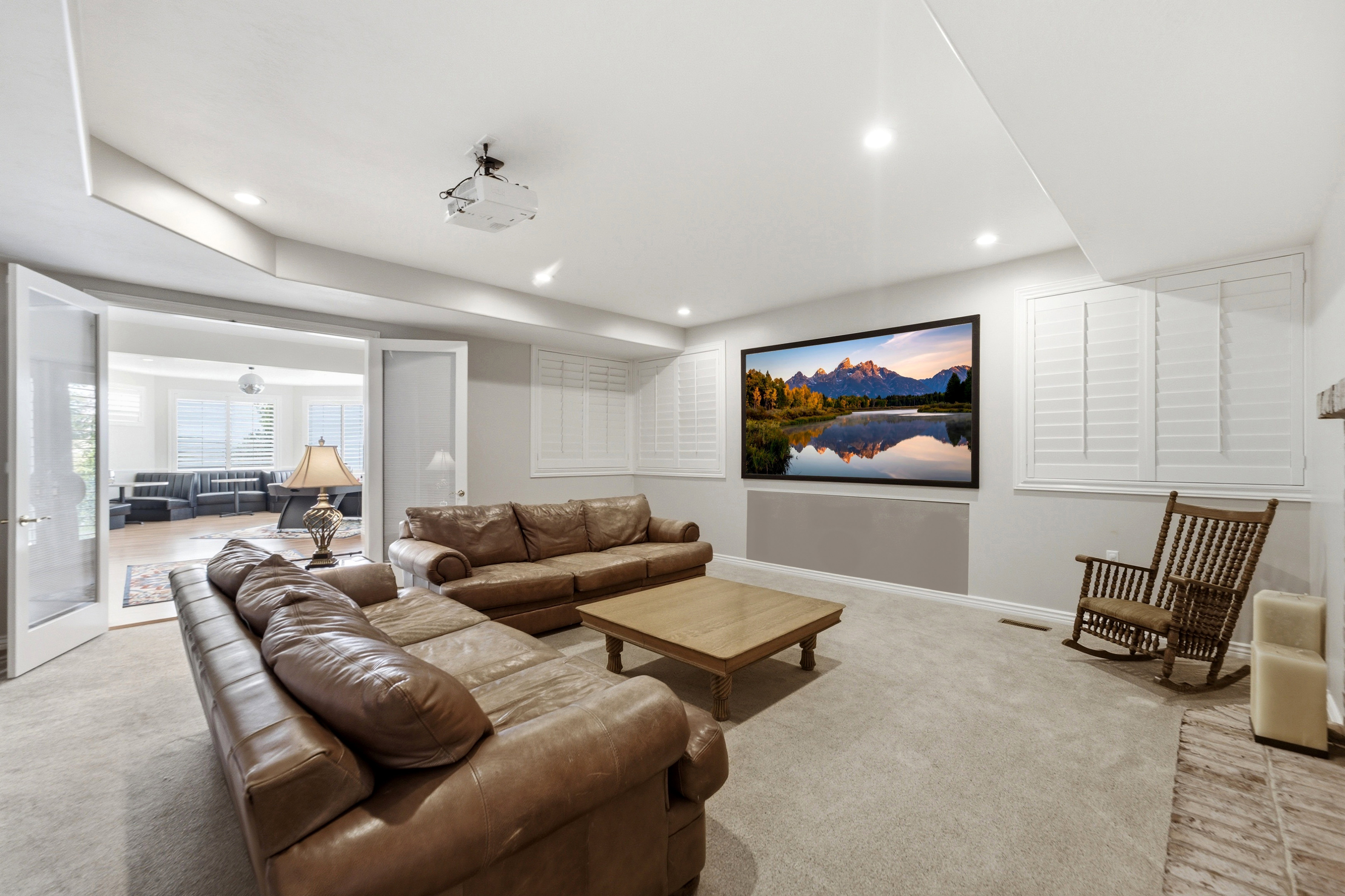 Entertainment space featuring a large projection screen, recessed lighting, and carpeted flooring