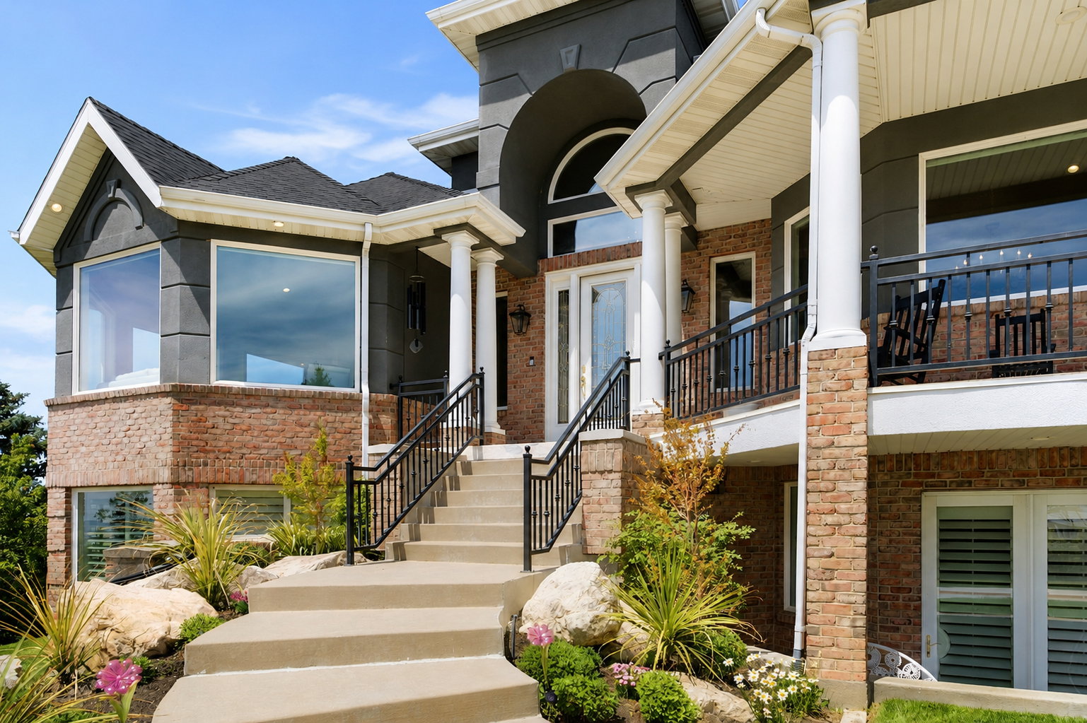 Grand exterior featuring a multi-level design with brick and stucco finishes