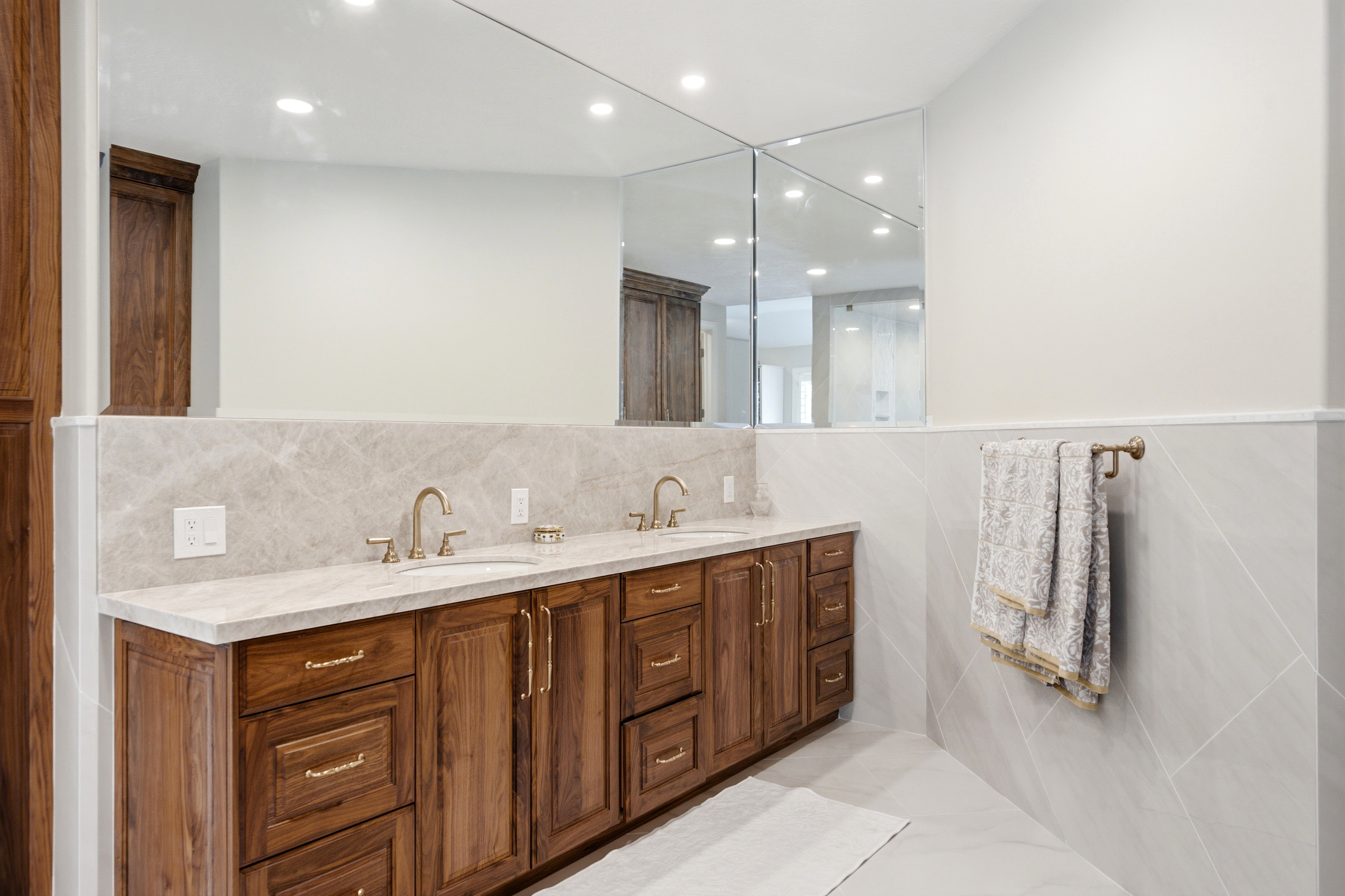 Double vanity featuring wood cabinetry, integrated sinks, stone countertops, and brass fixtures