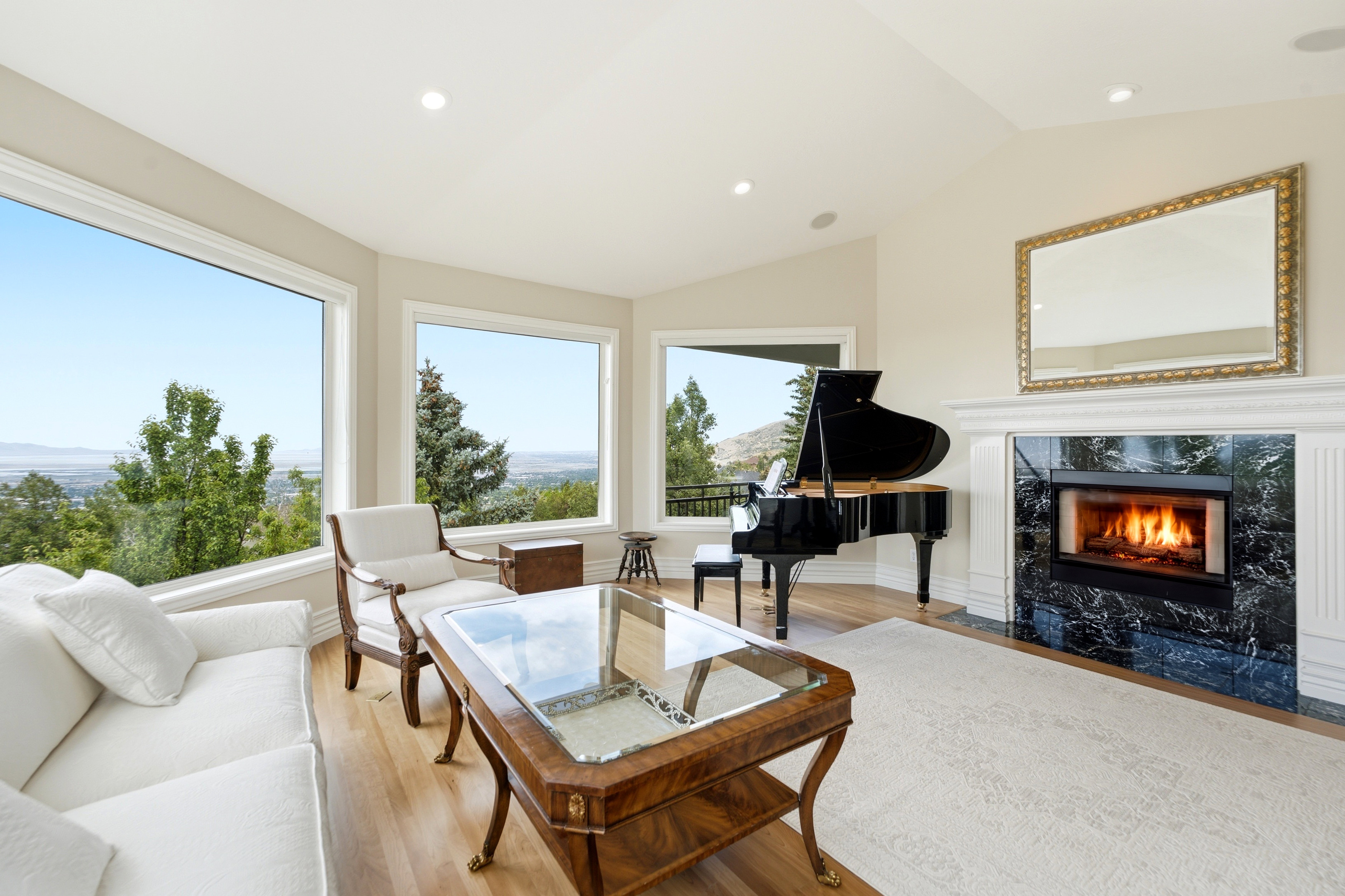 Spacious living area featuring large picture windows, a classic fireplace with a stone surround, recessed lighting, and wood-finish flooring