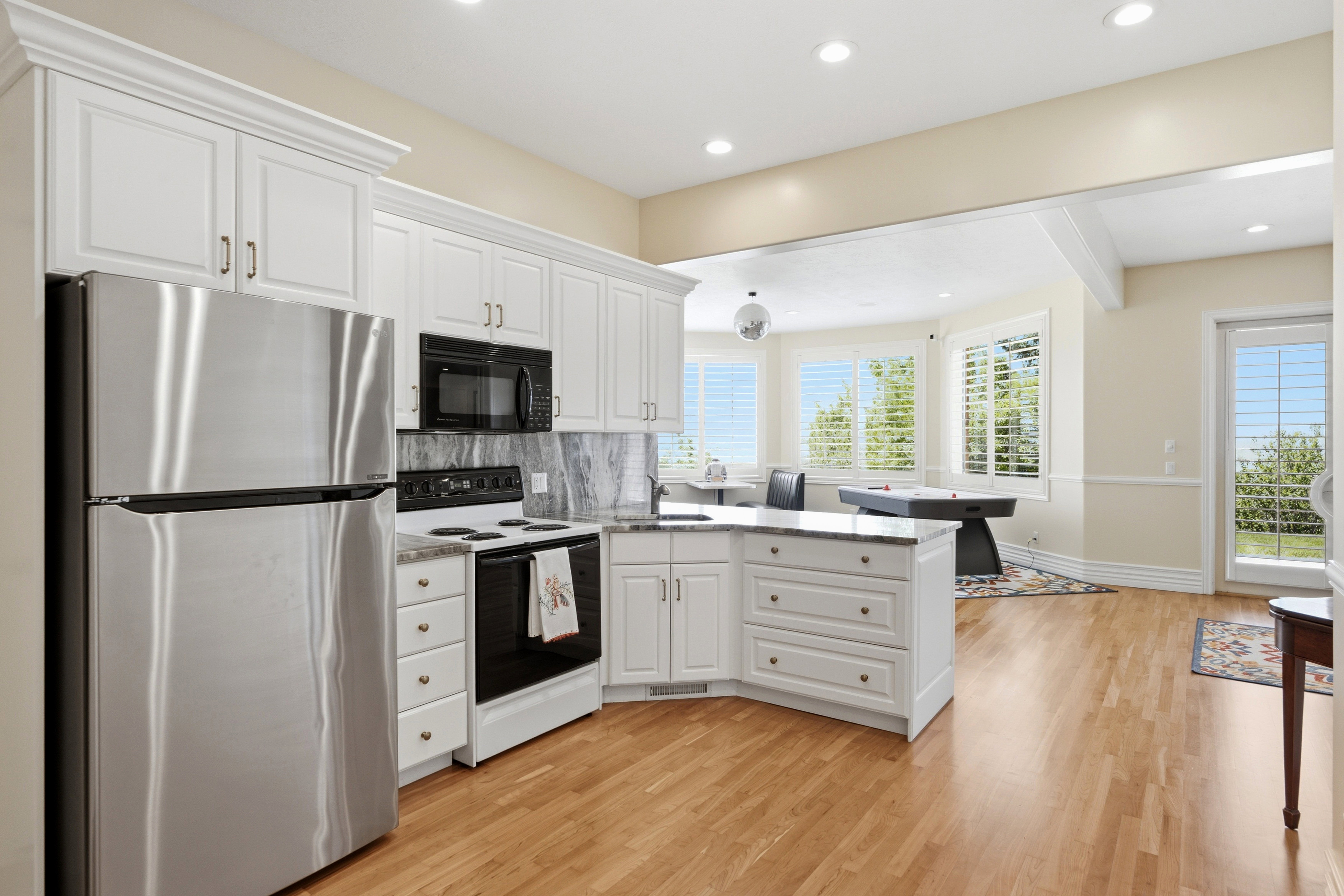 Full kitchen featuring white cabinetry, stainless steel refrigerator, black microwave, and black electric range