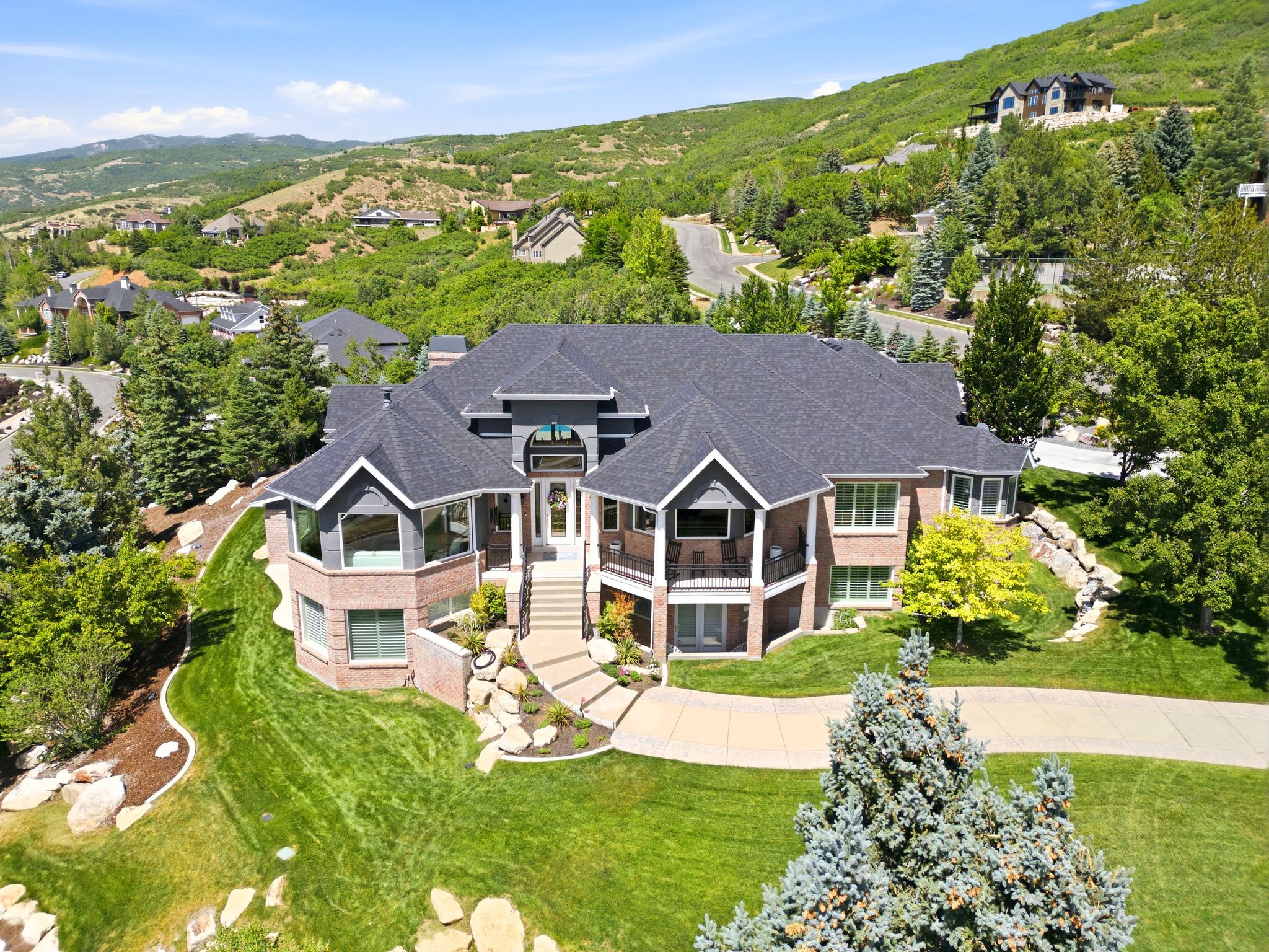 Grand residence featuring a dark gray roof, two balconies, and a brick and siding exterior