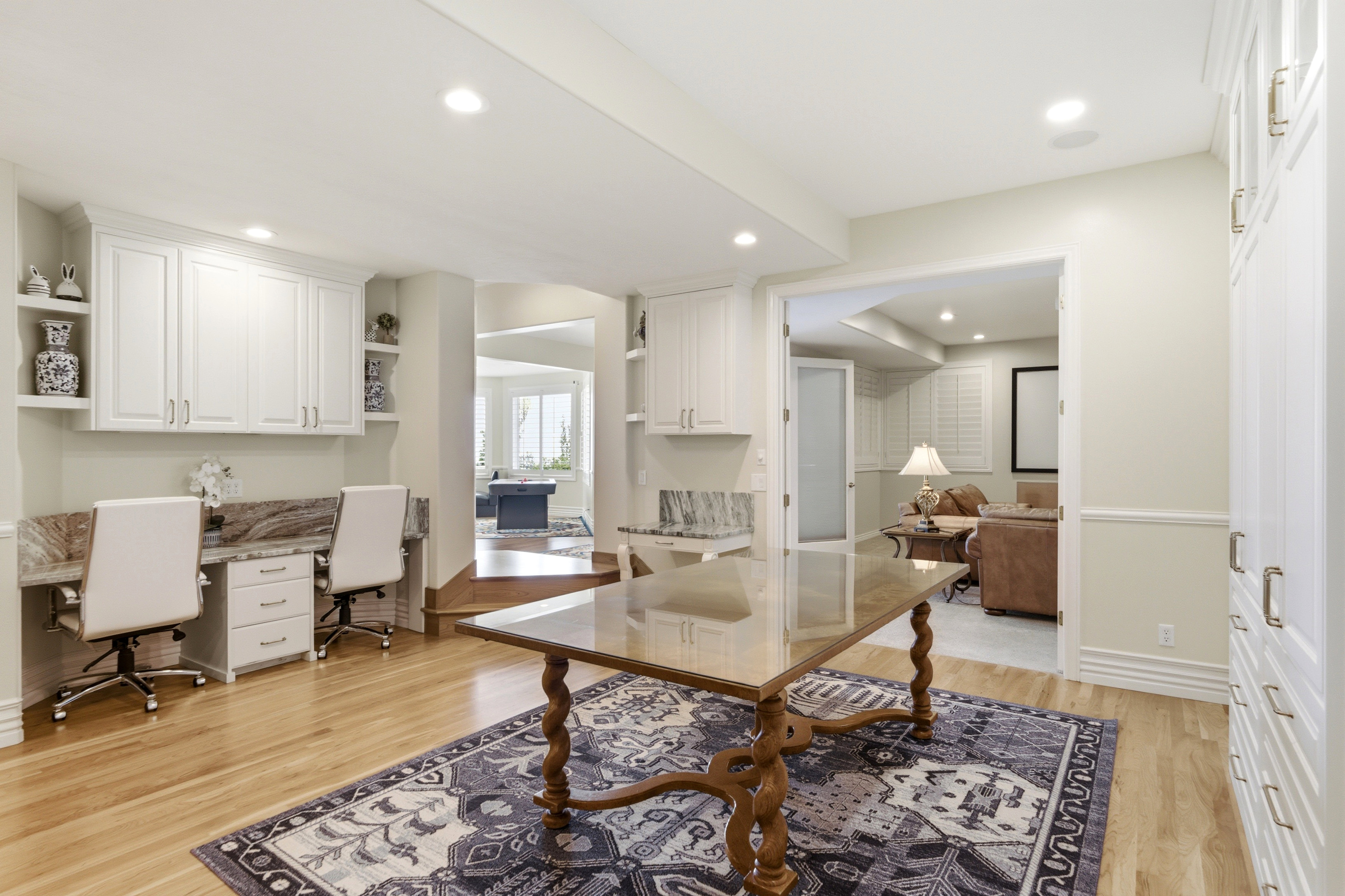 Dedicated workspace featuring built-in cabinetry, stone-finish countertops, and wood-finish flooring