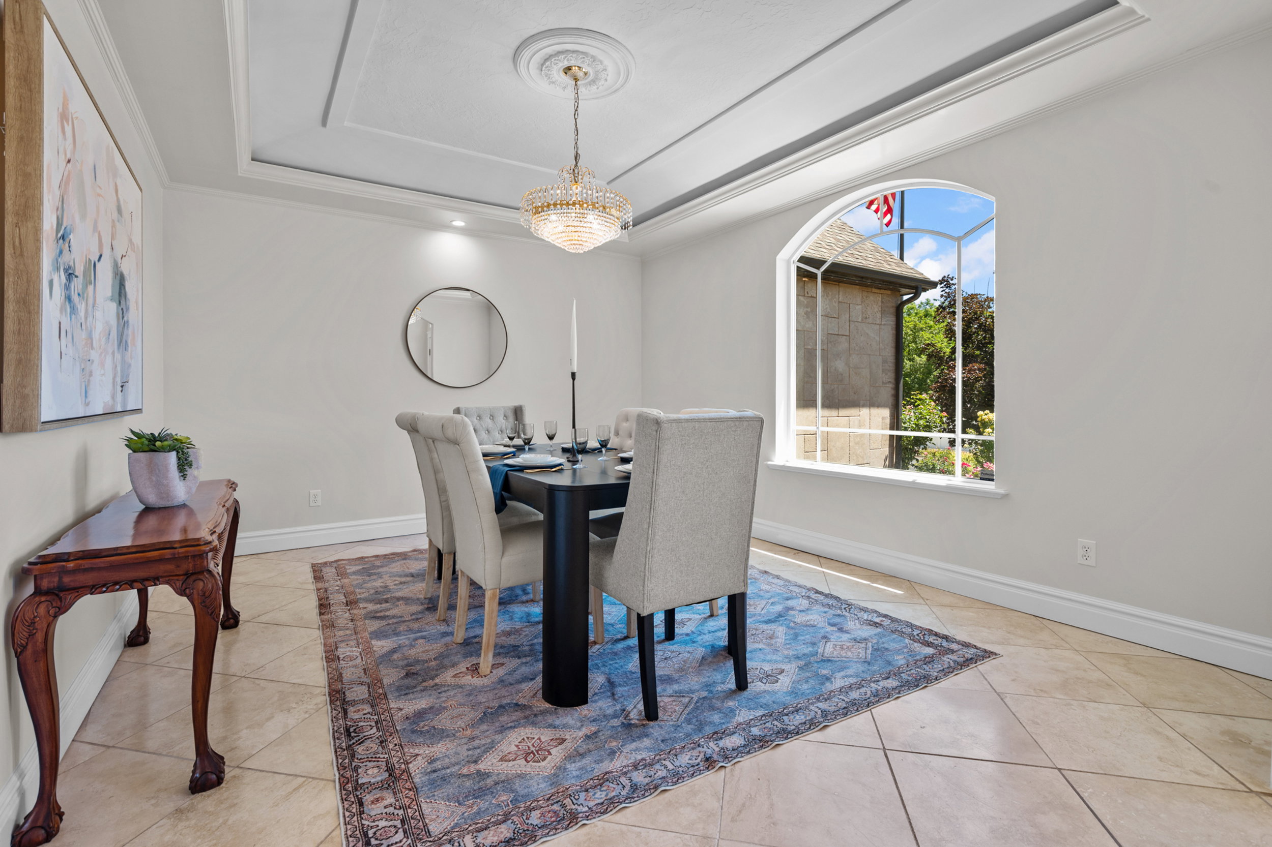 Dining area featuring a coffered ceiling with a Steinbach crystal chandelier, arched window, travertine flooring
