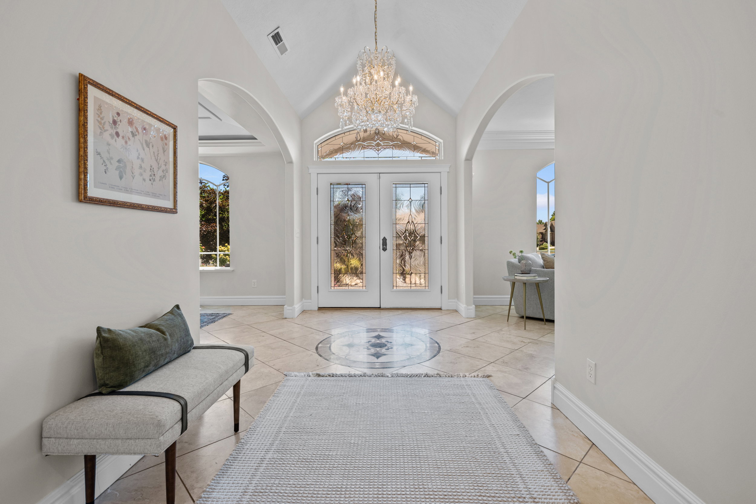 Grand entryway featuring arched doorways, a Steinbach crystal chandelier, and a travertine floor with an inlaid medallion