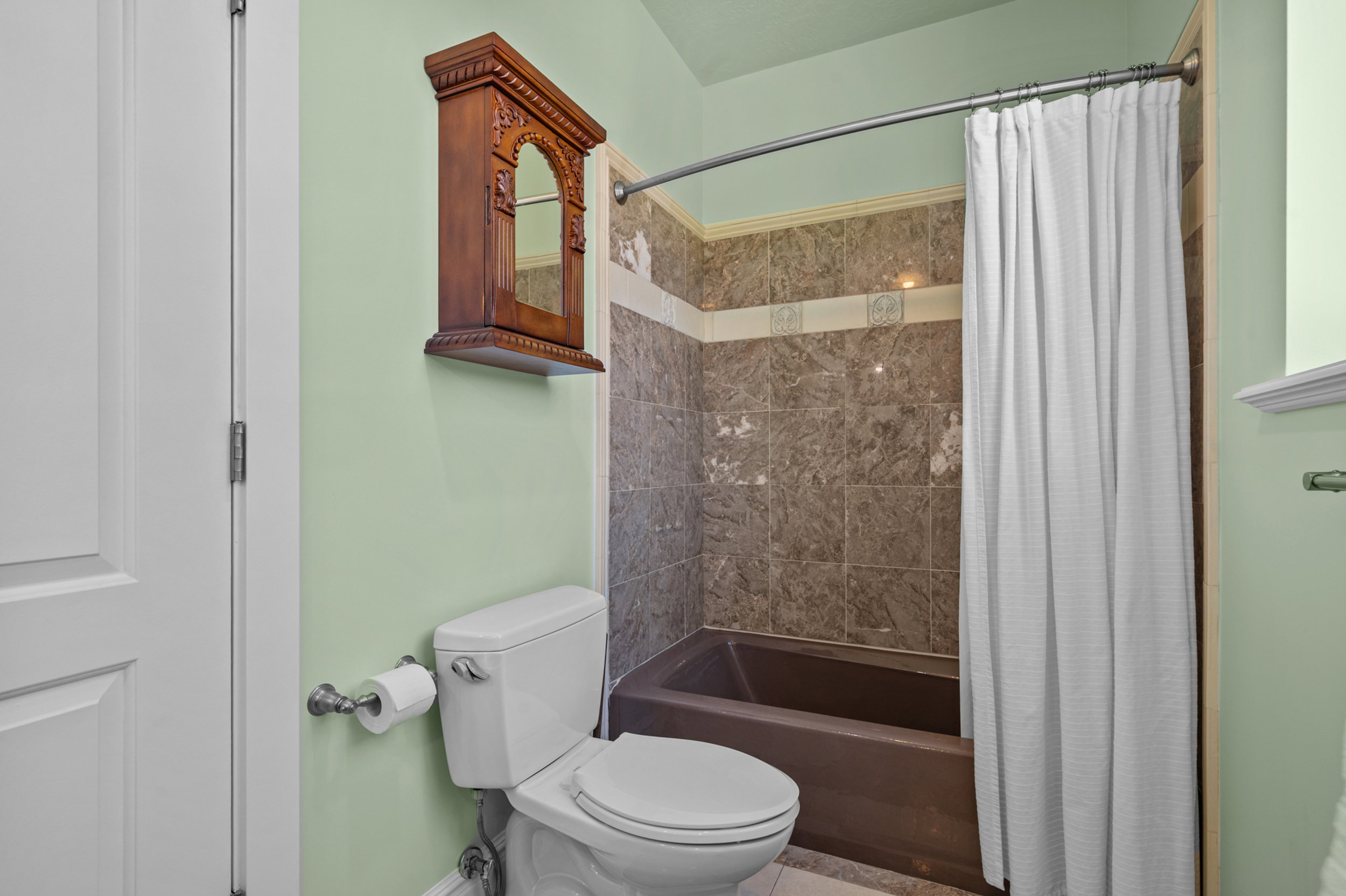 Bathroom featuring a white toilet, tile flooring, and a brown bathtub with coordinating wall tiles