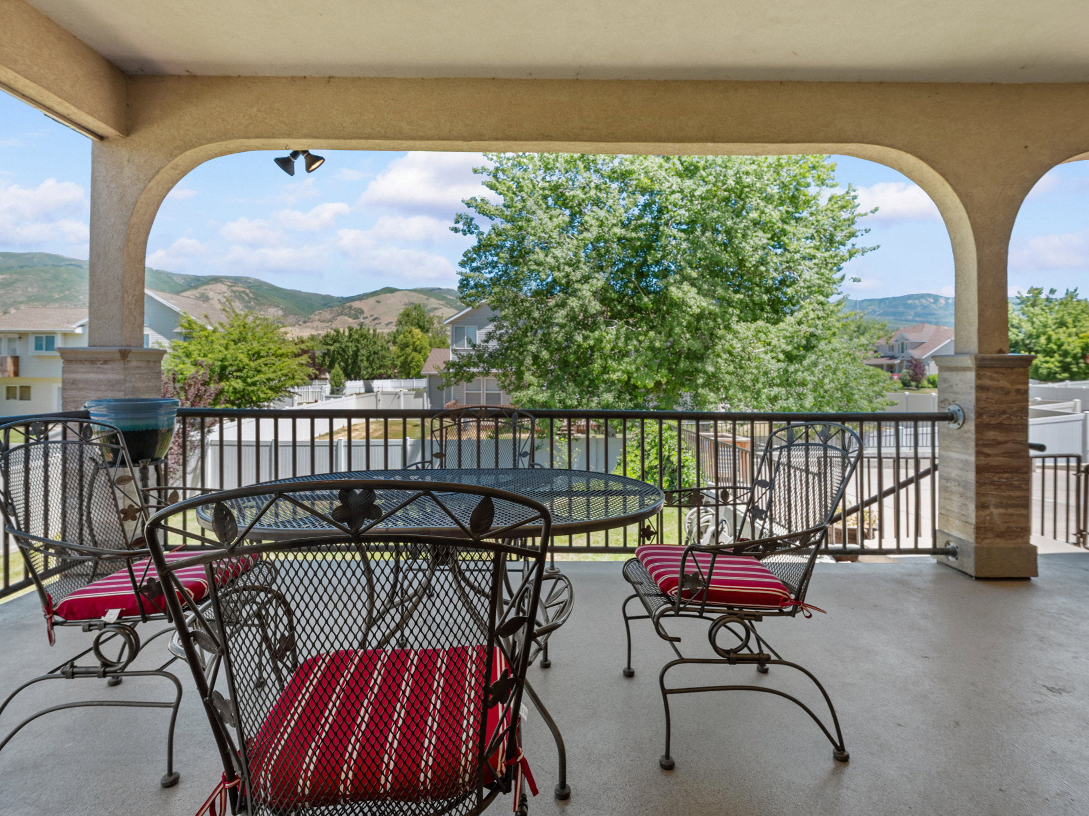 Covered outdoor patio featuring arched openings, a concrete floor, and a black metal railing