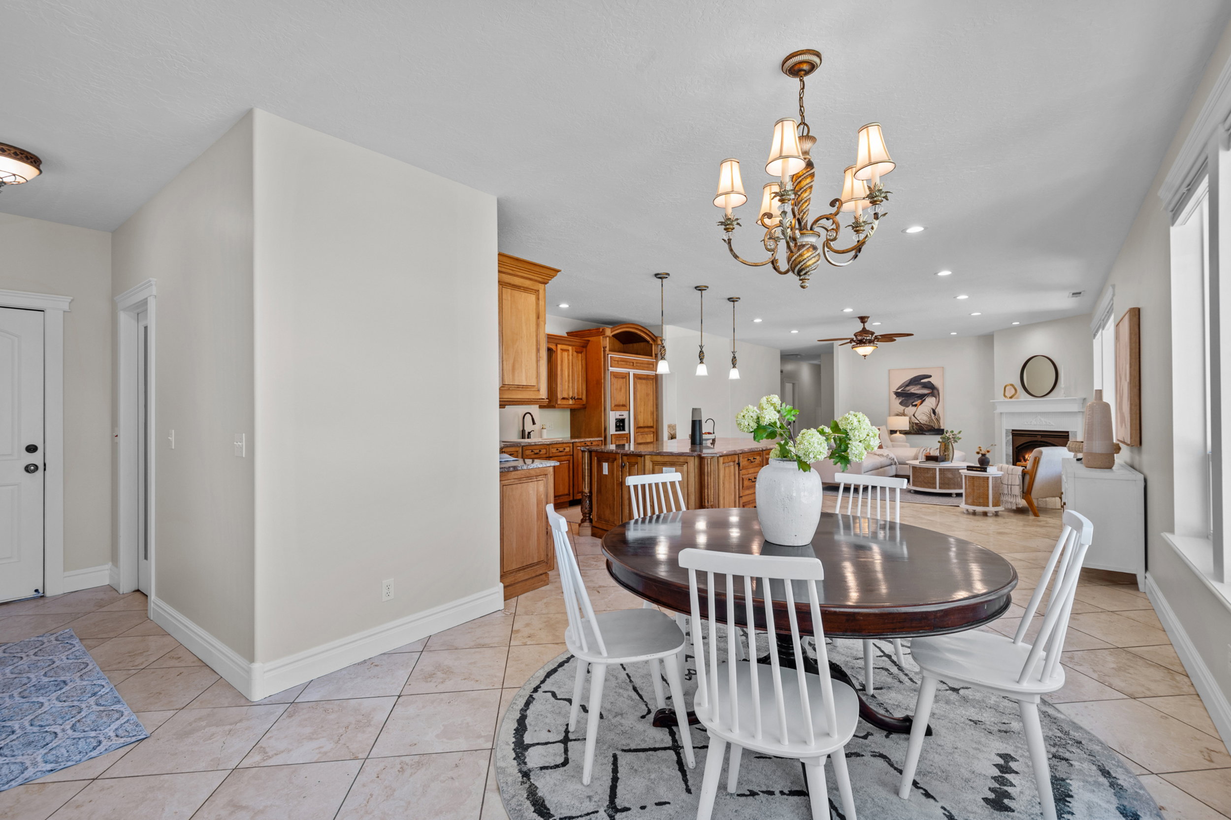 Travertine flooring extends through this open-concept interior, featuring a dining area with a multi-arm chandelier