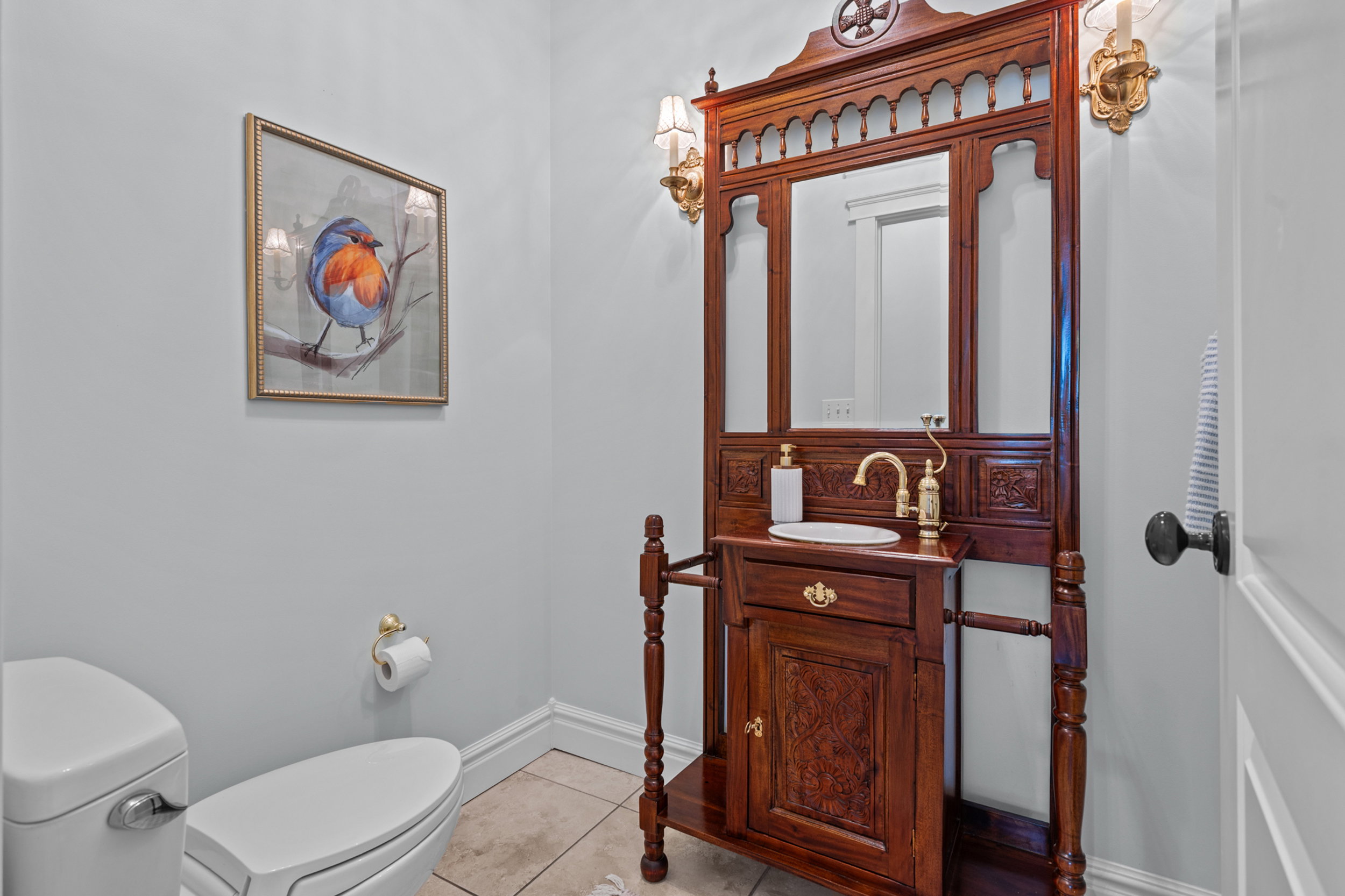 Custom antique vanity featuring a carved wood frame, integrated mirror, and a gold-finish faucet