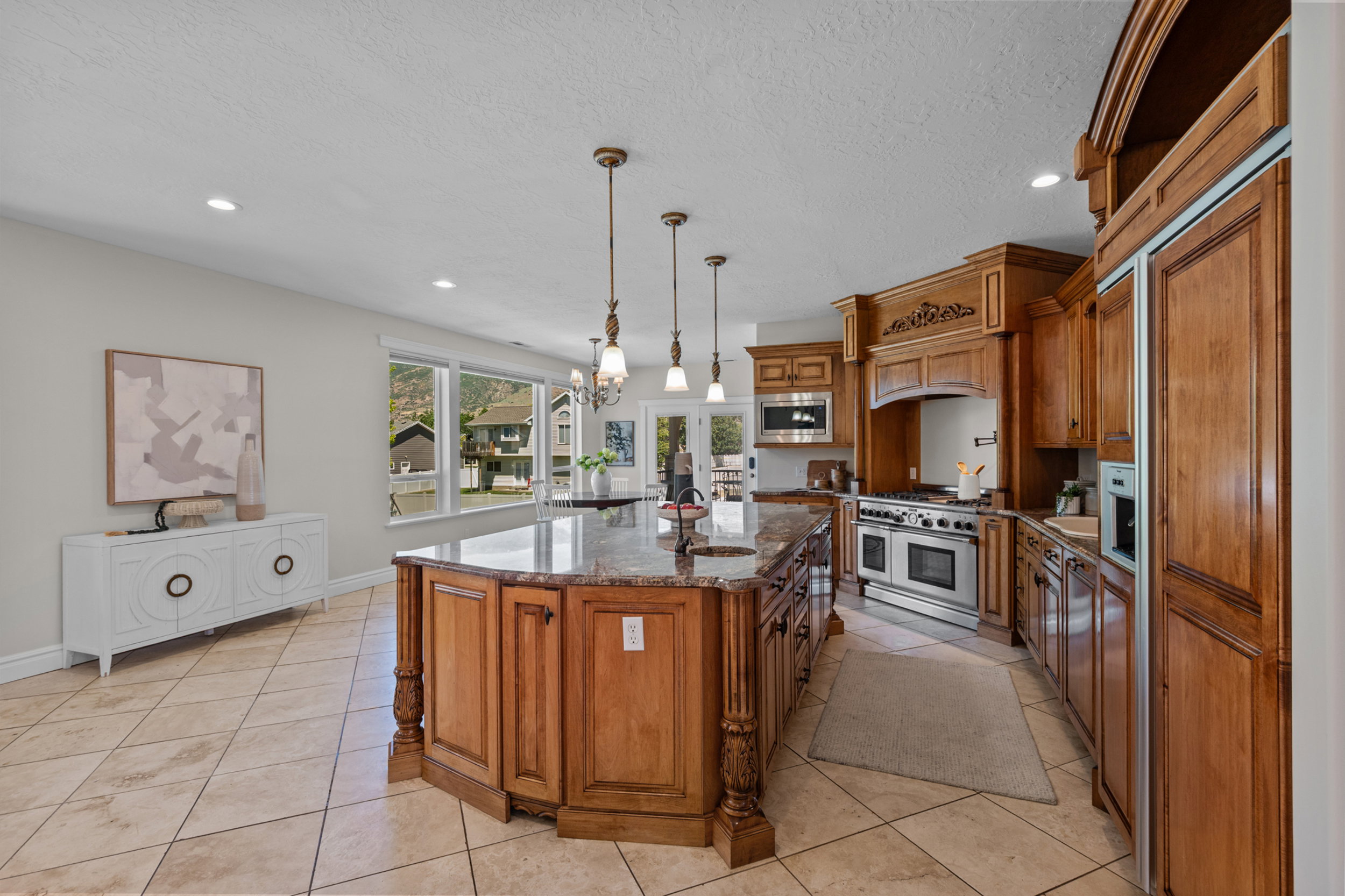 Gourmet kitchen featuring a large central island, ample wood cabinetry, built in cabinet faced appliances
