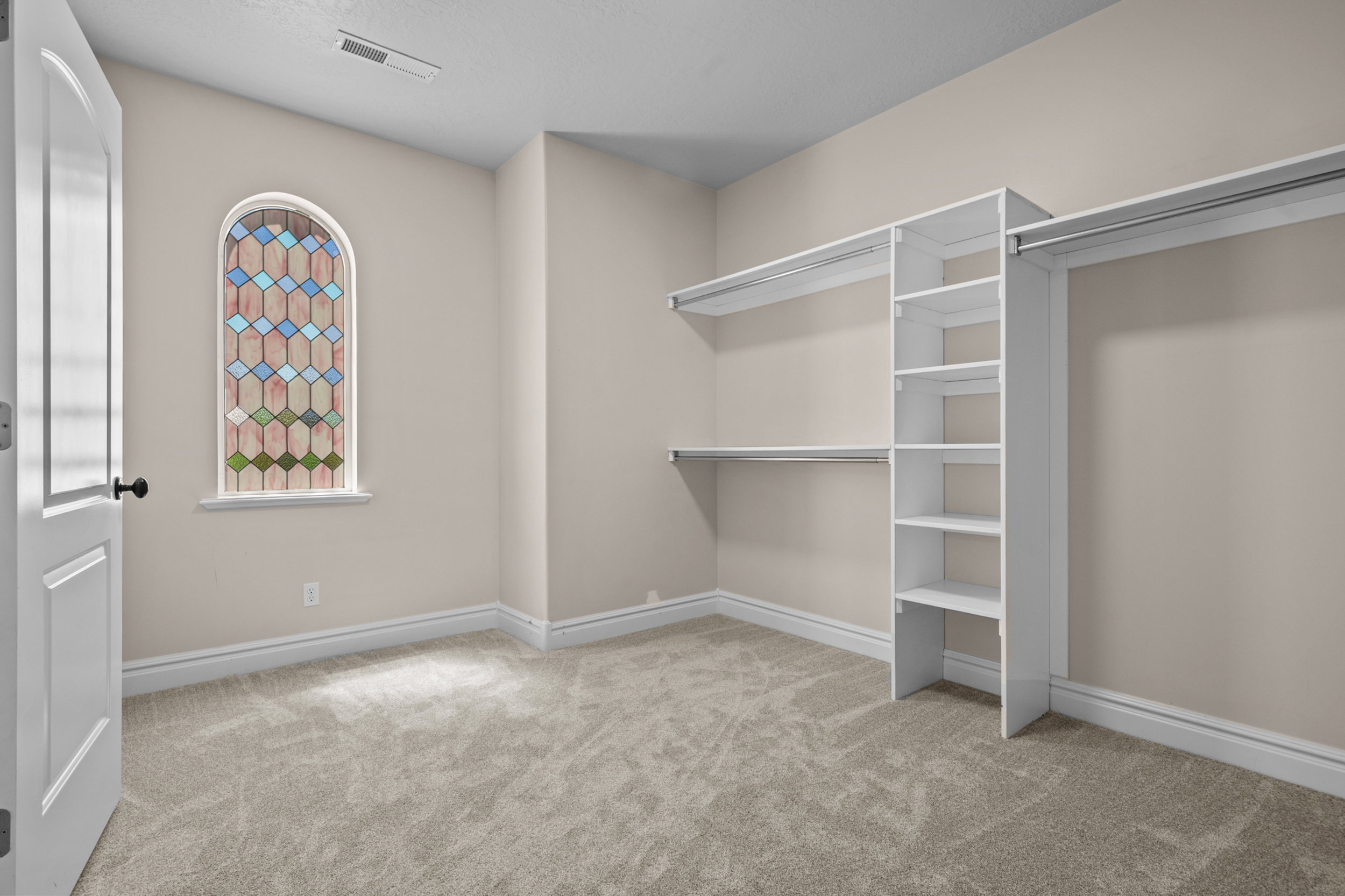 Interior room with light tan walls, light beige carpet, white baseboards, and a white architectural door
